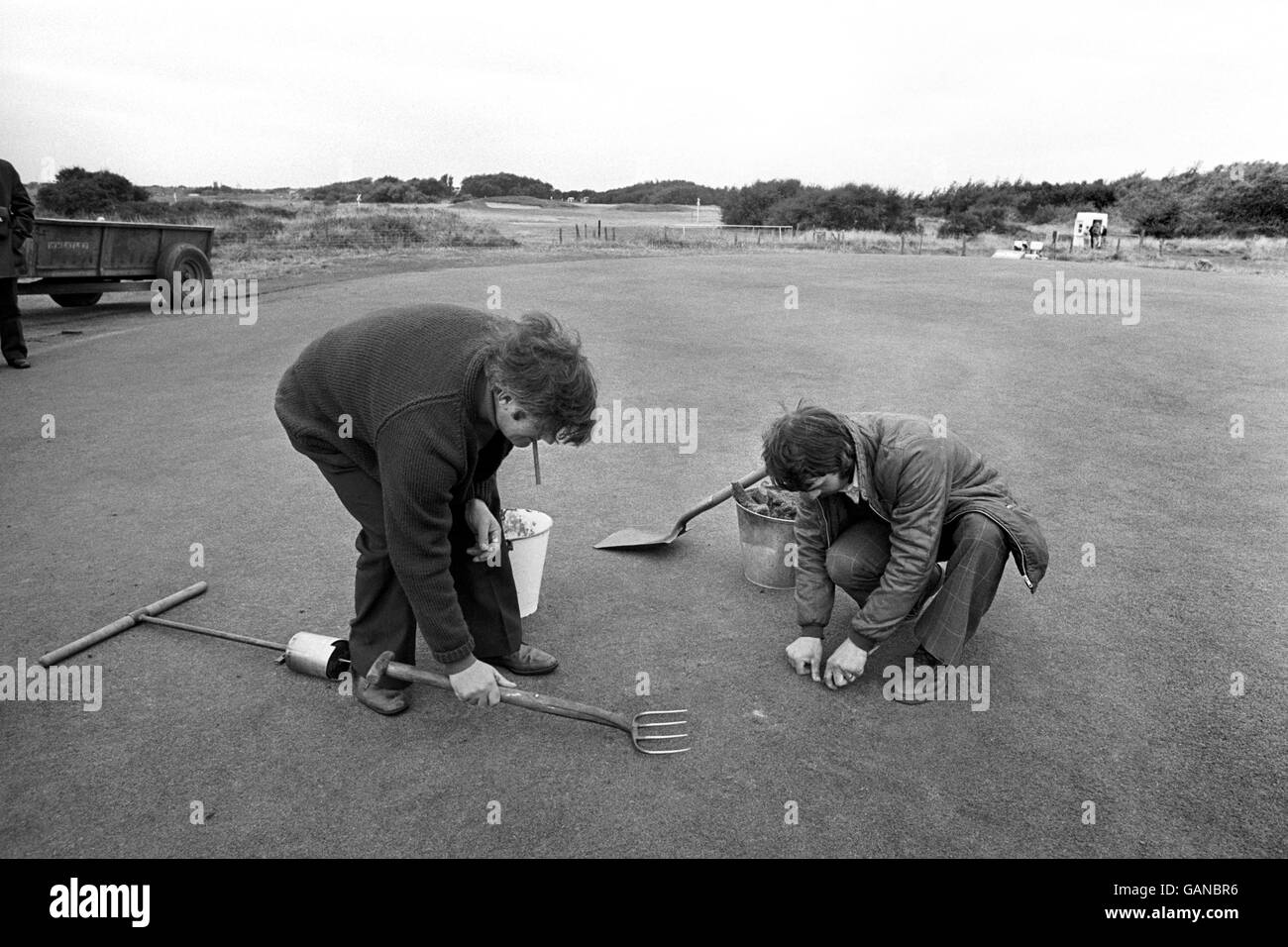 Le chef du green Jim MacDonald (à gauche) et son assistant Chris Whittle travaillent sur le 10e green. Les dommages sont concentrés autour du trou. Un nouveau trou a été coupé à environ 12 pieds de la zone endommagée. Banque D'Images
