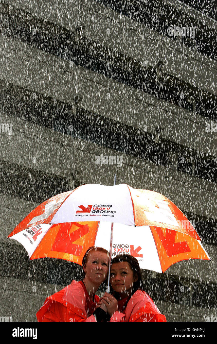 Courtnay Mullen (l) et Frances McCann (r), de la principale école de théâtre écossaise Gampta, qui se produit sous une machine à pluie à la gare de Cowcaddens dans le cadre du premier festival de métro de Glasgow. Banque D'Images