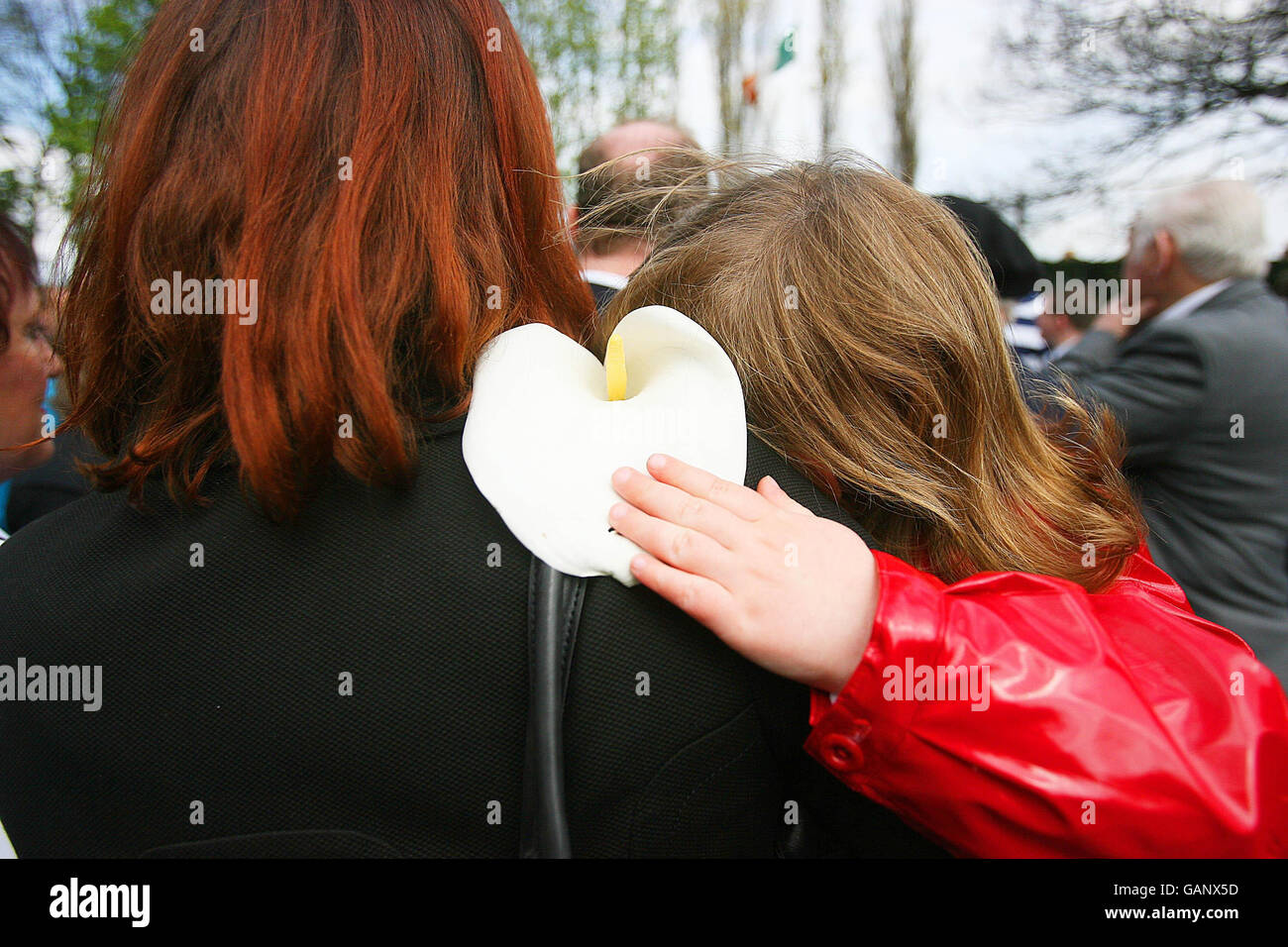 Une jeune fille repose sur l'épaule de ses mères qui embrase un Lily de Pâques lors de la commémoration annuelle de Fianna Fail Arbour Hill à Dublin. Banque D'Images