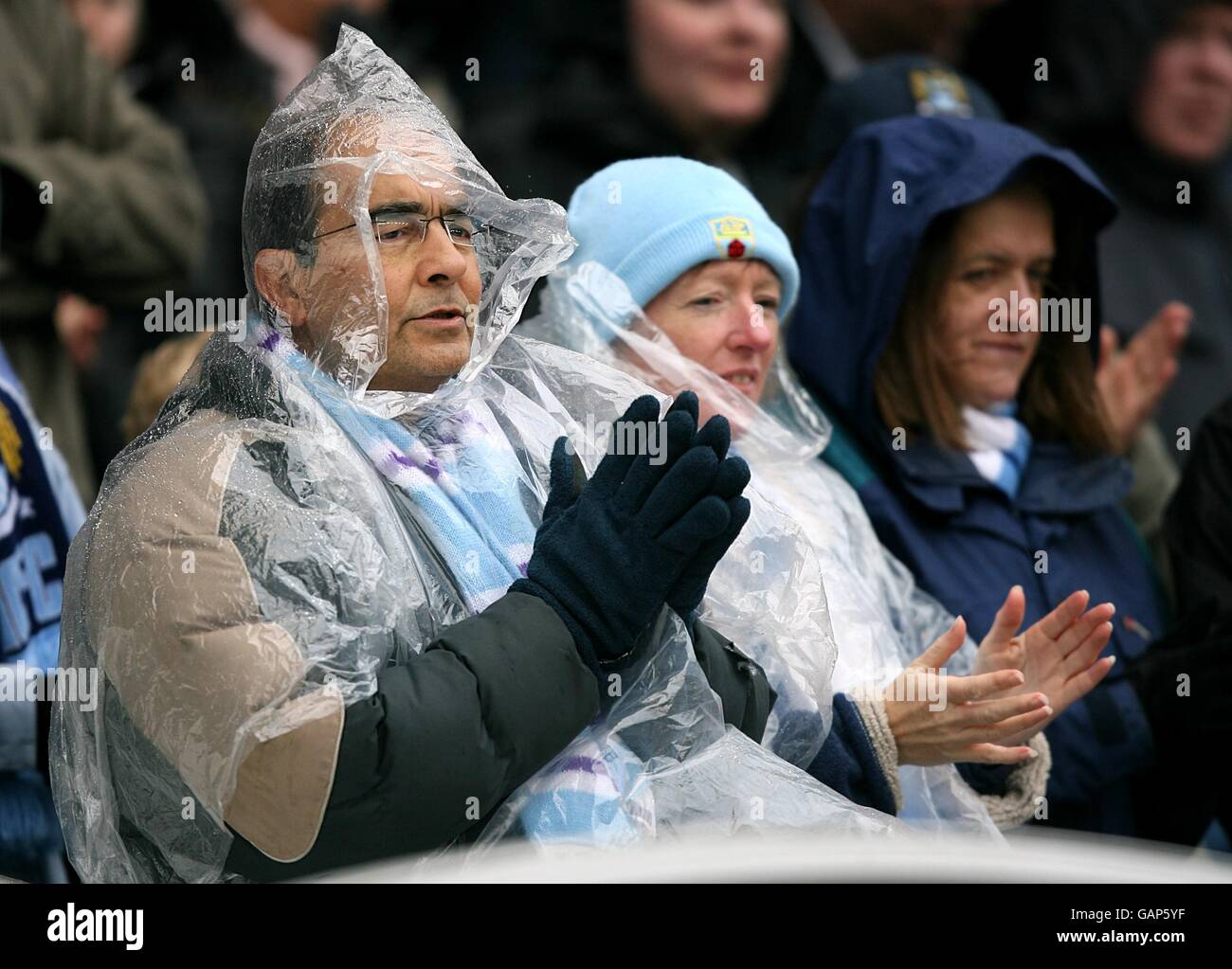 Football - Barclays Premier League - Manchester City v Portsmouth - City of Manchester Stadium. Les fans se protéger de la pluie dans les stands Banque D'Images