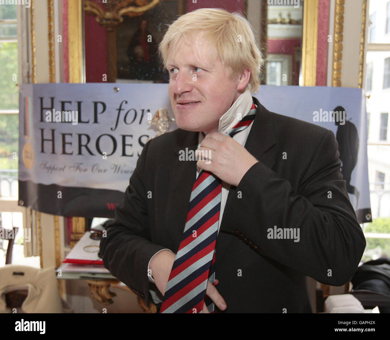 Le maire de Londres Boris Johnson met sur une aide pour les héros cravate acheté d'un stand de vente d'aide pour les héros articles pour recueillir de l'argent pour l'organisme de bienfaisance au Club naval et militaire de St James's Square, Londres. Banque D'Images