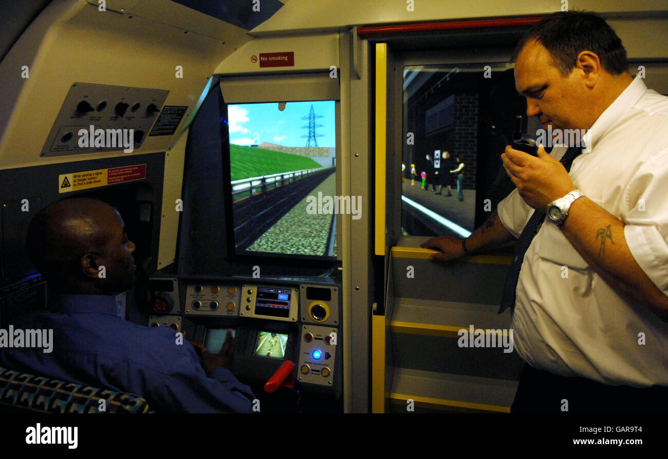 Un conducteur de train souterrain de Londres utilise l'un des simulateurs de train améliorés au centre de contrôle de service Neasden, tandis qu'un instructeur regarde, dans le nord de Londres, en préparation d'un nouveau système de signalisation automatique qui sera mis en œuvre sur la ligne Jubilee. Banque D'Images