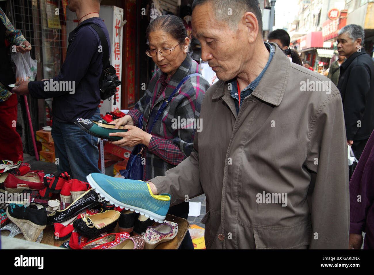 L'homme chinois et sa femme sont à la recherche de chaussures bon marché  qu'ils peuvent acheter. D'autres personnes sont vues derrière. Qibao Old  Street, Beijing, Chine Photo Stock - Alamy