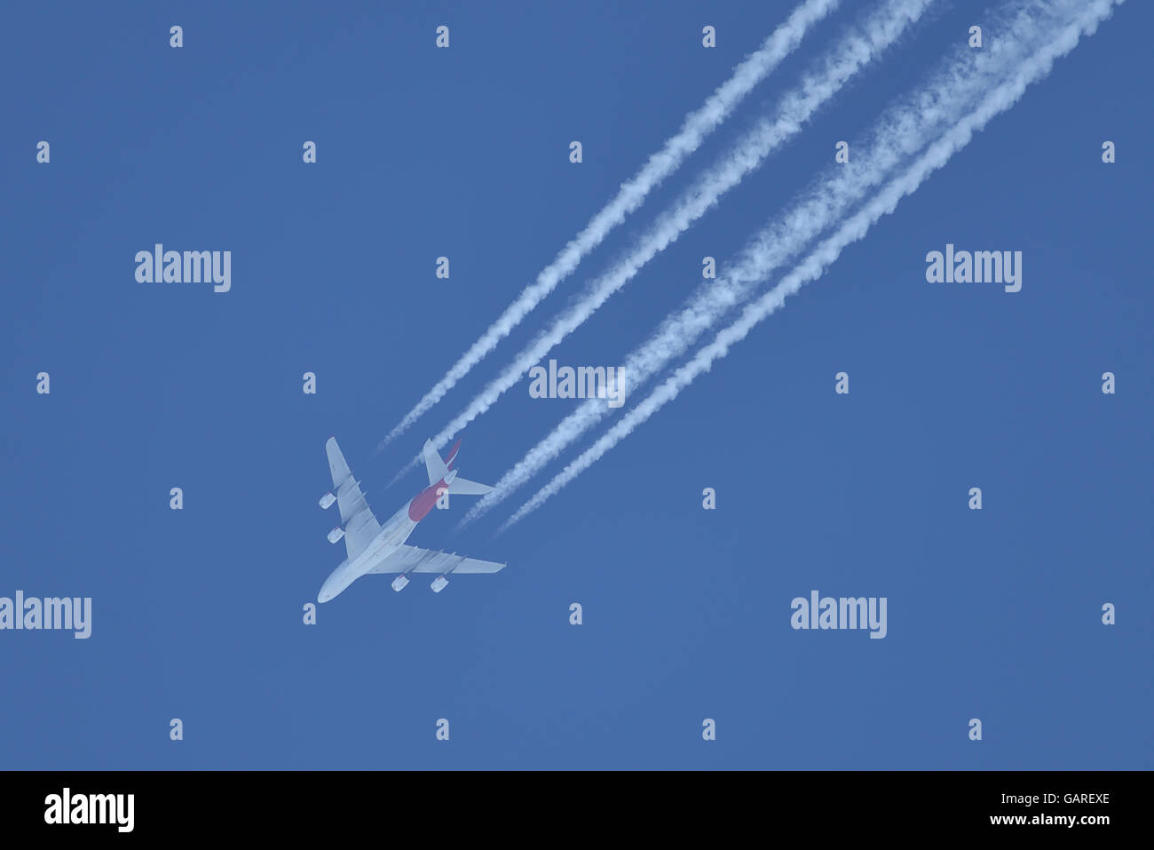 Avion en vol sur le ciel bleu laissant derrière les lignes blanches Banque D'Images