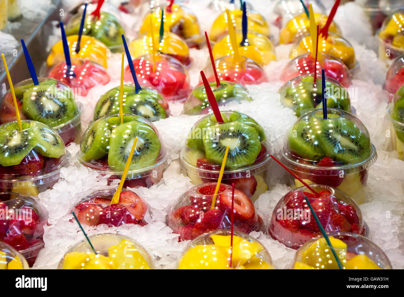 Cocktail de fruits frais salade dans des gobelets en plastique sur un étal du marché Banque D'Images