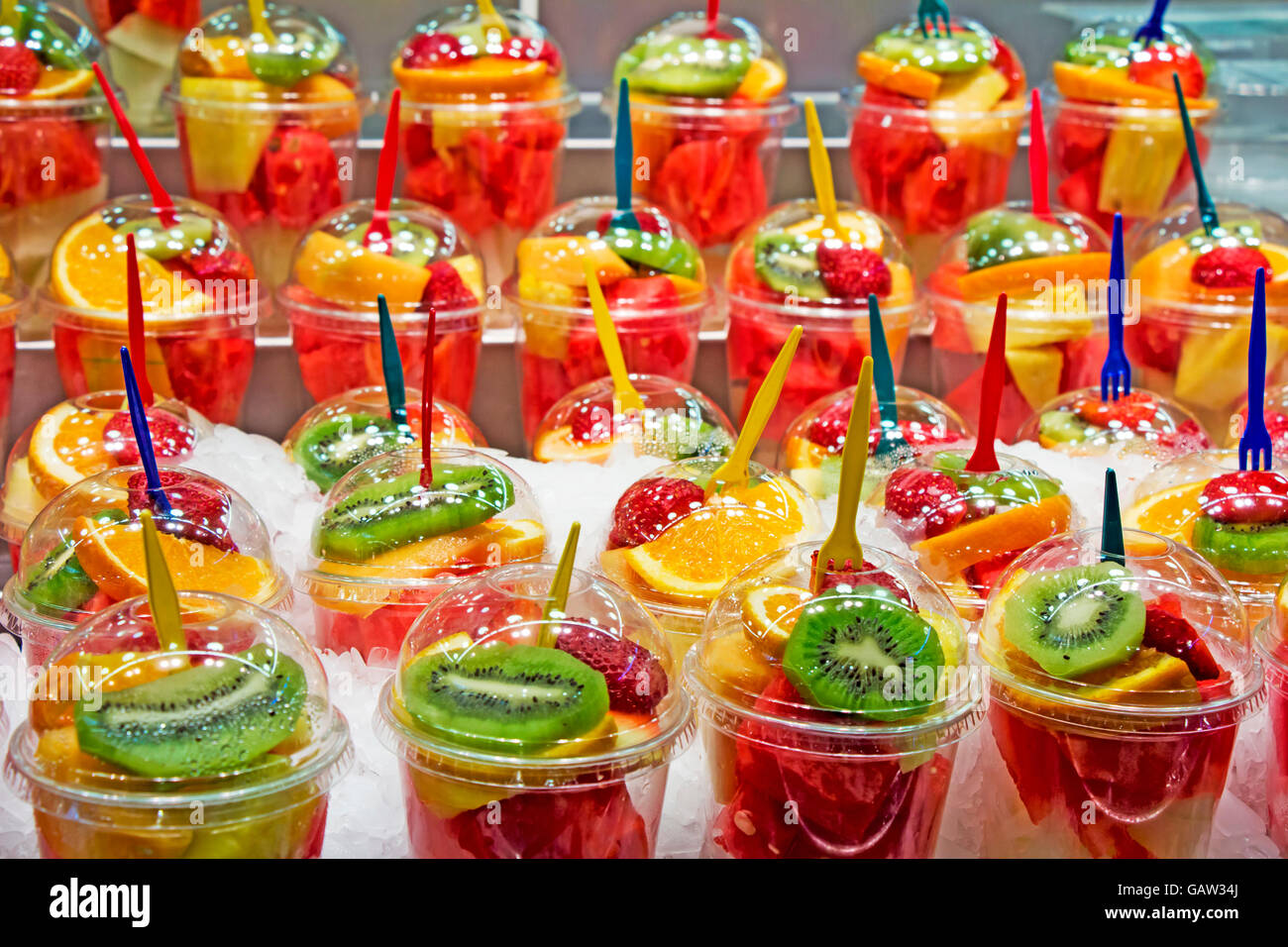 Cocktail de fruits frais salade dans des gobelets en plastique sur un étal du marché Banque D'Images