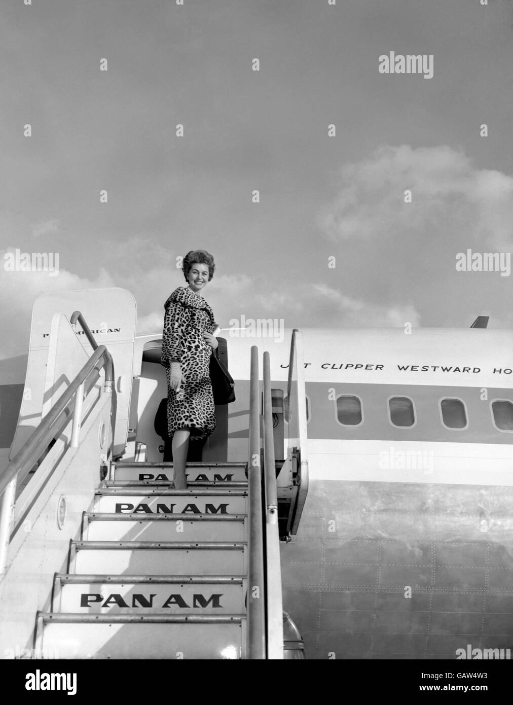 Dans un manteau de peau léopard et sans éclat, l'actrice Cyd Charisse monte à bord d'une tondeuse à jet panaméricaine à l'aéroport de Londres aujourd'hui (mercredi) sur son chemin à Hollywood après trois mois de tournage au Royaume-Uni. Banque D'Images