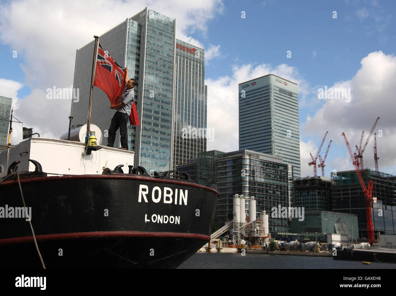 Un membre de l'équipage lève un drapeau à bord du SS Robin, alors que le navire se prépare à quitter West India Dock, Canary Wharf, Londres, pour être remorqué par remorqueur à Lowestoft pour restauration. Banque D'Images