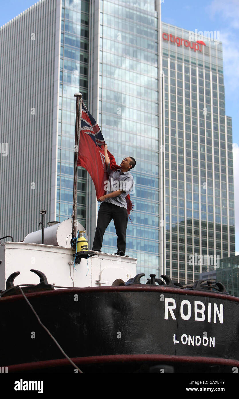 Un membre de l'équipage lève un drapeau à bord du SS Robin, alors que le navire se prépare à quitter West India Dock, Canary Wharf, Londres, pour être remorqué par remorqueur à Lowestoft pour restauration. Banque D'Images