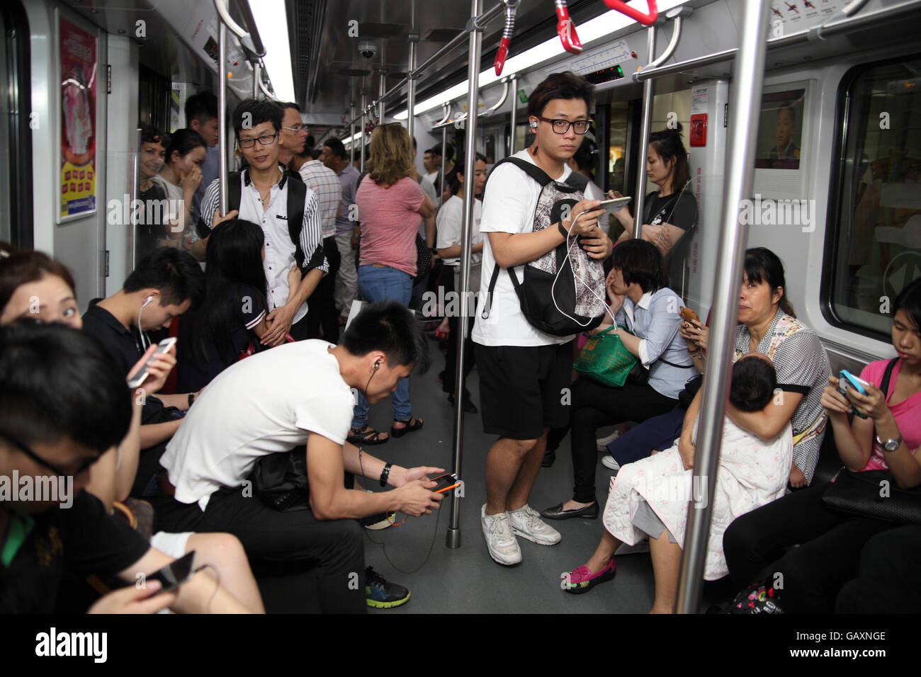 La circonscription du peuple chinois Guangzhou Metro train, certains assis d'un certain rang, certains jouant avec leurs smartphones. Guangzhou. Banque D'Images