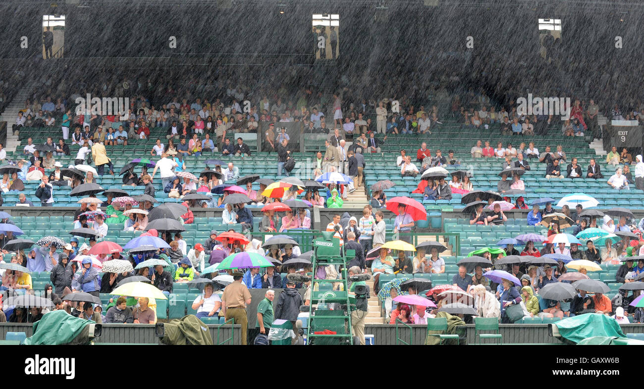Les fans s'assoient sous la pluie sur le court central, car le jeu est retardé pendant les championnats de Wimbledon 2008 au All England tennis Club de Wimbledon. Banque D'Images