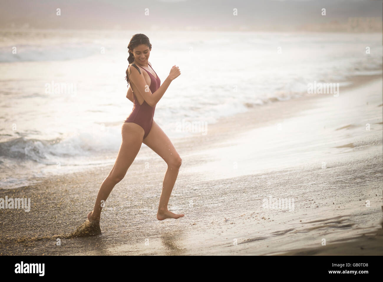 Jeune femme séduisante en maillot à la plage avant le coucher du soleil, heure Banque D'Images
