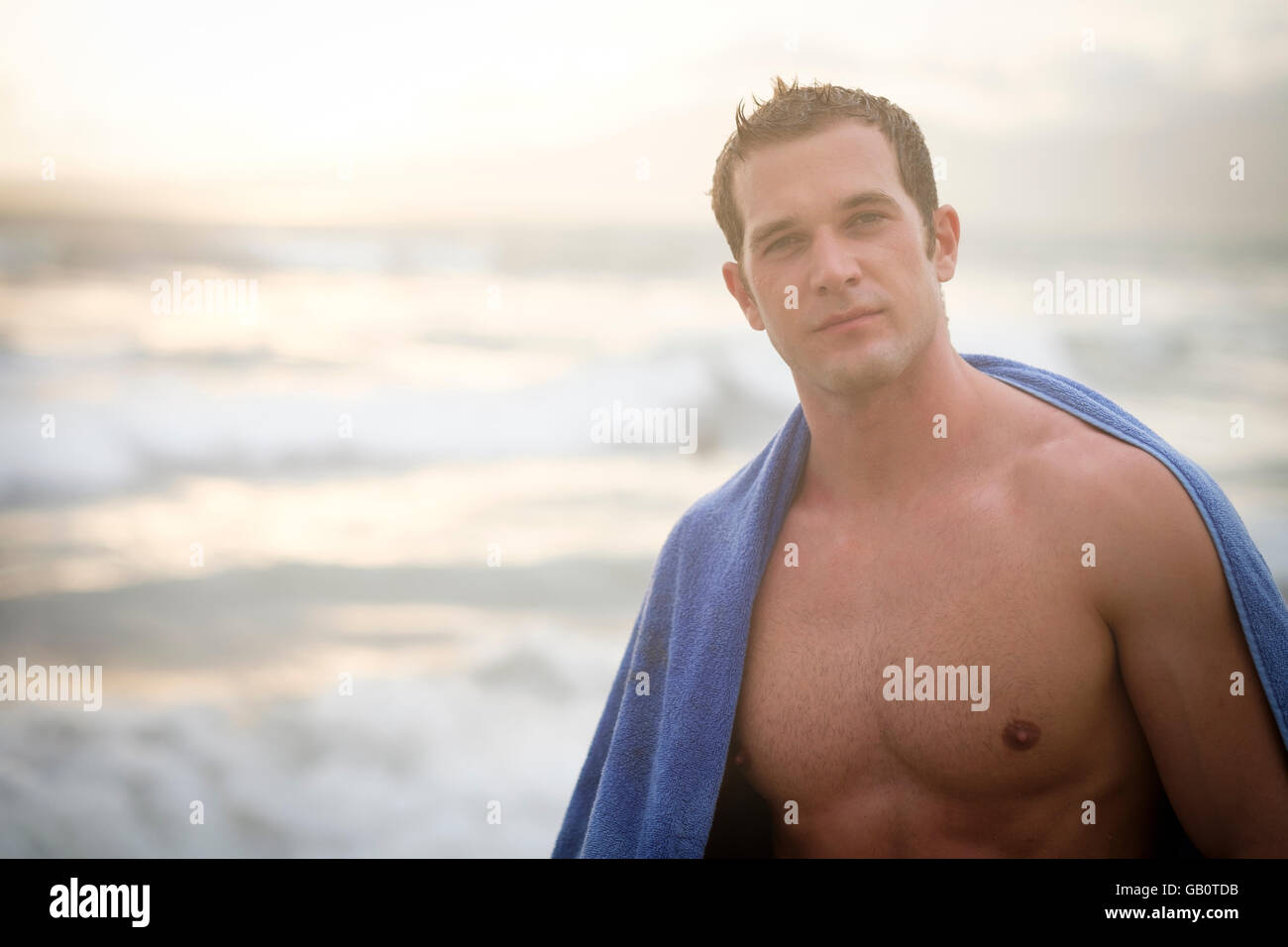 Portrait de jeune homme musclé avec une serviette sur ses épaules à une plage Banque D'Images