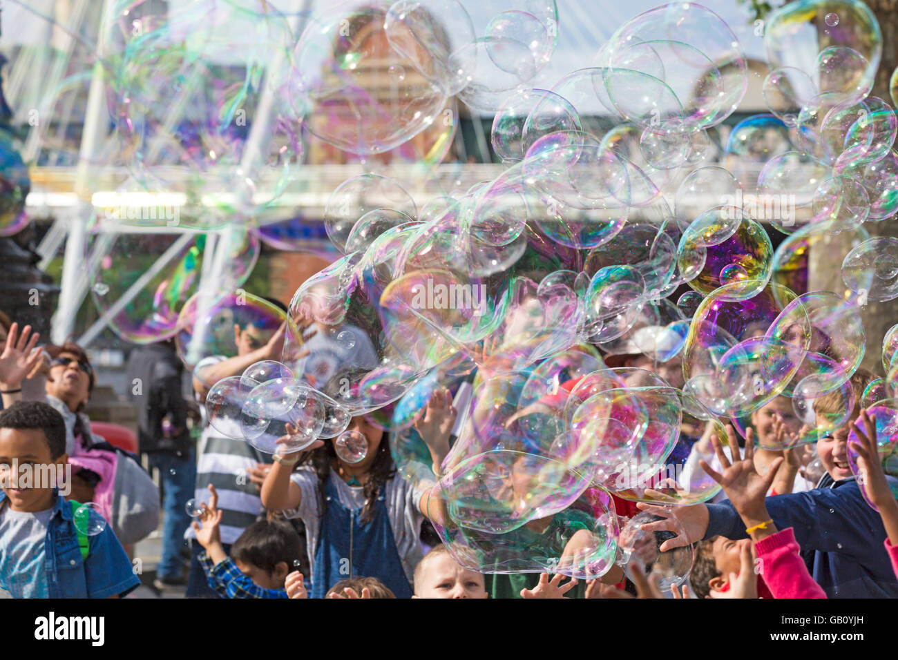 Les enfants d'essayer de suivre les grandes bulles à Southbank, Londres en Juillet Banque D'Images