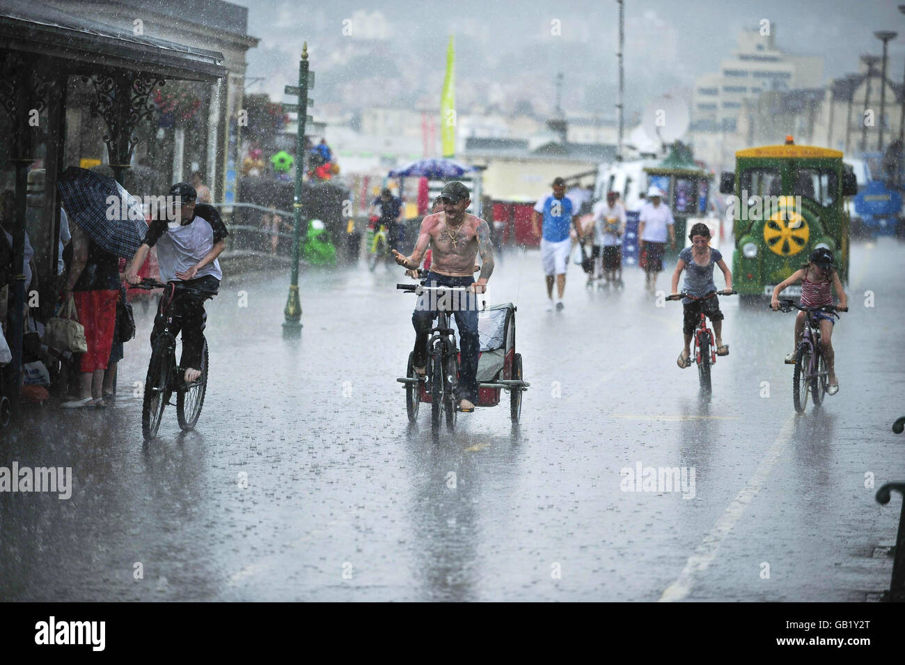 Les cyclistes sont pris dans un bref déluge d'été sur la promenade de Weston-super-Mare. Banque D'Images