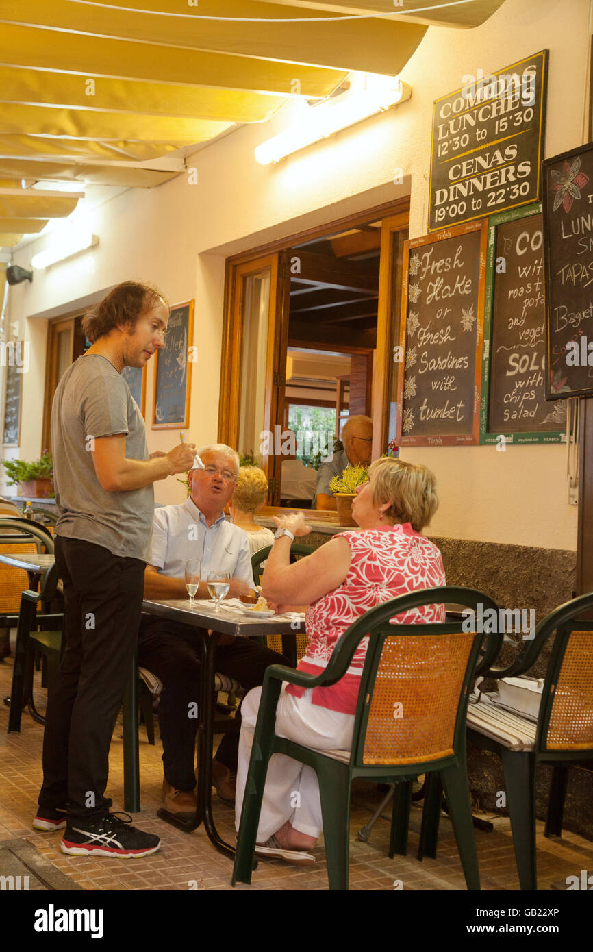 Afin de Waiter taking un couple de personnes âgées dans un restaurant, Puerto Pollensa, Mallorca ( Majorque ), Îles Baléares Espagne Europe Banque D'Images