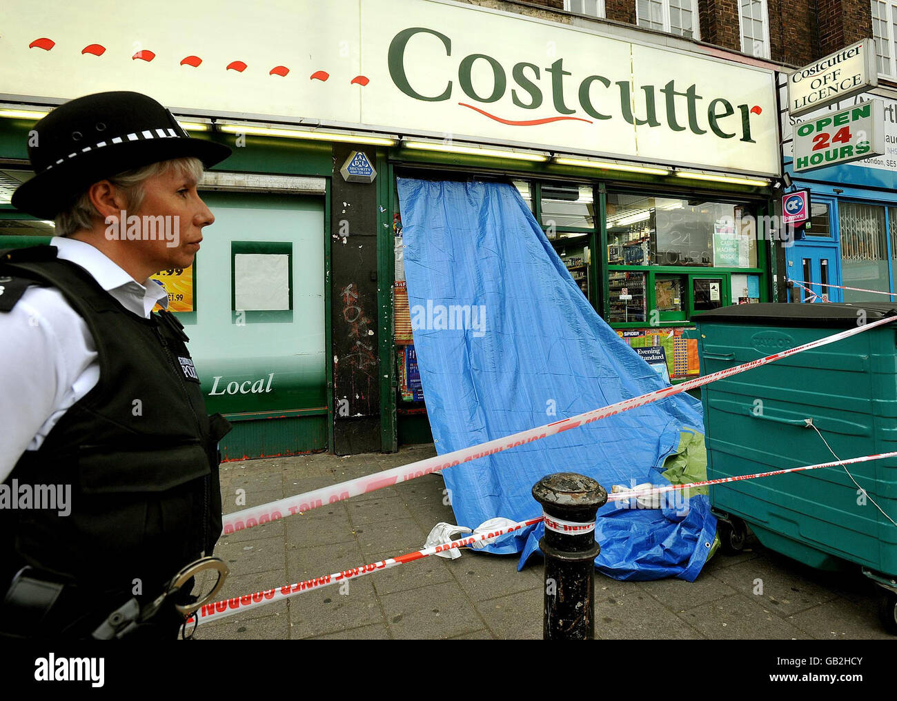 Un officier de police métropolitaine se trouve à l'extérieur d'un magasin Costcutter à Walworth, dans le sud de Londres, où un adolescent a été abattu après son entrée dans le dépanneur. Banque D'Images