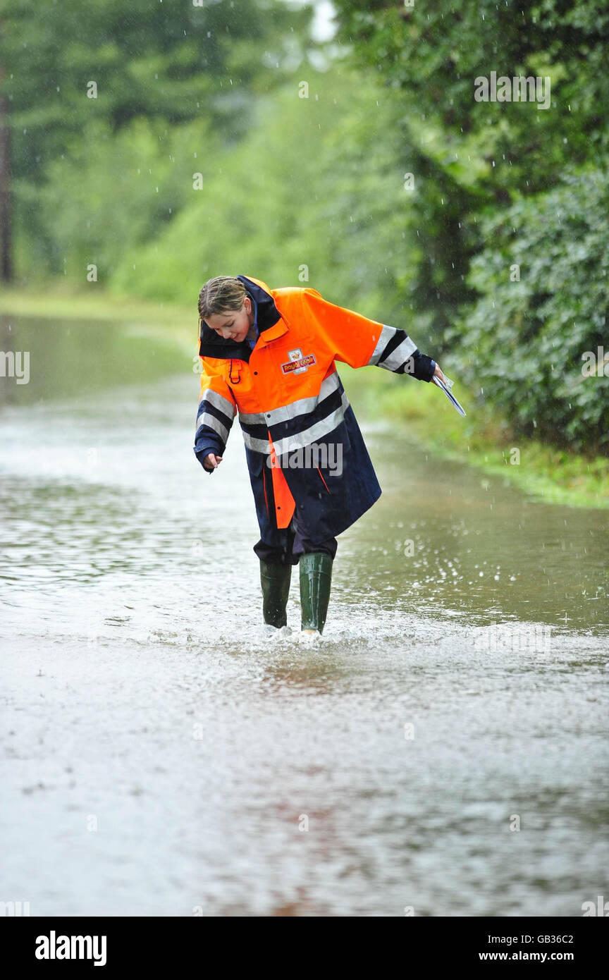 La postwoman Elizabeth Brain, 23 ans, qui est basée au dépôt de Cenderford du Royal Mail, livre le courrier dans ses bottes wellington par l'eau de crue sur Rodney Sands à Gloucestershire, à côté de la rivière Severn. C'est une région qui inonde régulièrement et Elizabeth livre le courrier, peu importe le temps, même si, à cette occasion, la route avait inondé si mal qu'elle ne pouvait pas passer pour livrer à quelques maisons plus loin dans la voie. Banque D'Images