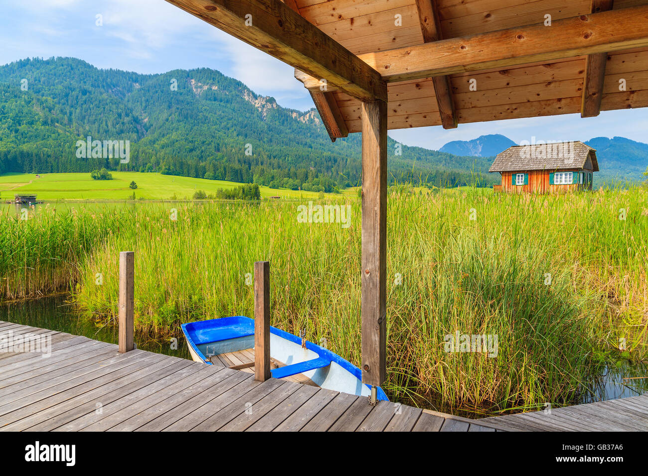 Amarrage bateau de pêche bleu en bois sur la rive de la jetée du lac Weissensee en Carinthie paysage estival de la terre, de l'Autriche. Banque D'Images