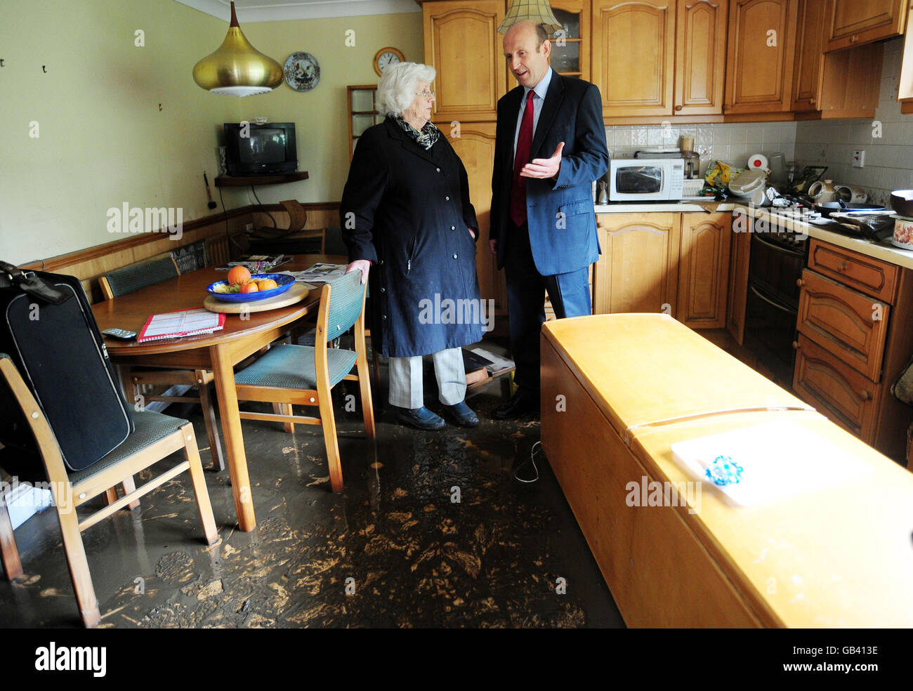 Le ministre de la reprise des inondations, John Healey, parle au médecin à la retraite, Elspeth Wilkinson, dans sa cuisine endommagée par les inondations de sa maison à Morpeth, dans le Northumberland. Banque D'Images