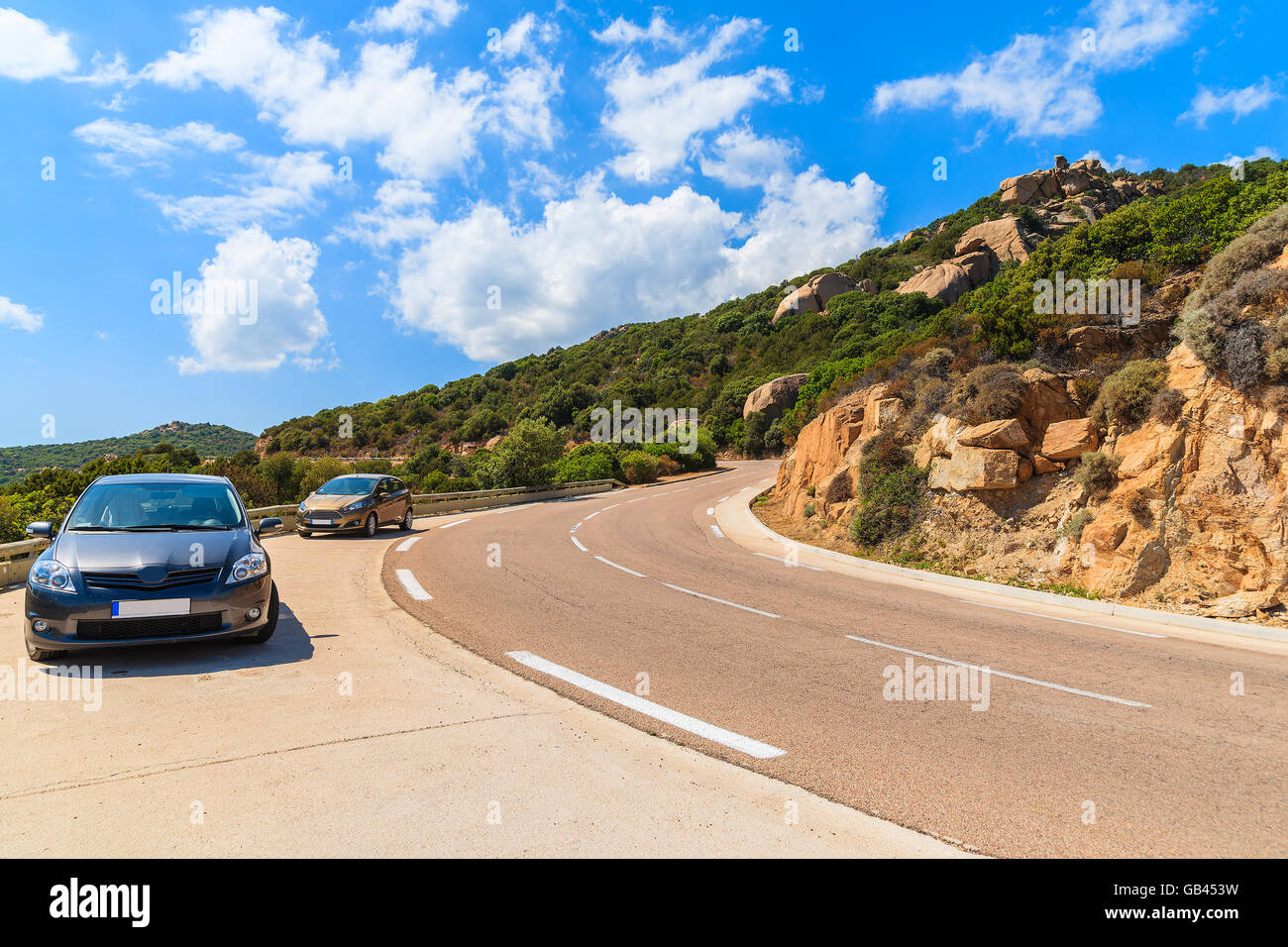 Parking voitures sur le long d'une route de montagne pittoresque au milieu des rochers sur l'île de Corse, France Banque D'Images