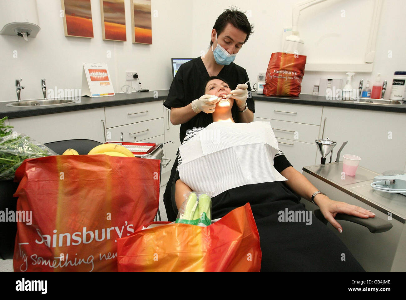 Le Dr lance Knight examine un patient en chirurgie dentaire dans un magasin de Sainsbury à sale, Manchester. Il s'agit du premier supermarché de chirurgie dentaire au Royaume-Uni et vise à rendre les soins dentaires plus accessibles au public. Banque D'Images