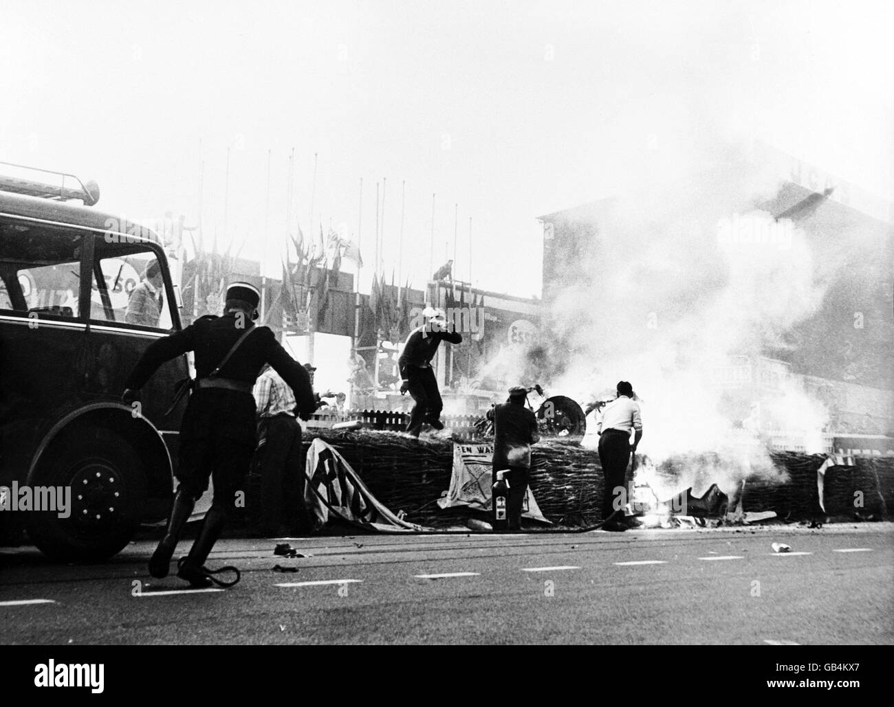 Un policier se déforme pour aider les pompiers à étouffer l'incendie qui a ravagé la Mercedes de Pierre Levegh, qui a explosé sur la dernière ligne droite, envoyant des gros morceaux de sa voiture voler dans la foule, entraînant 83 morts Banque D'Images