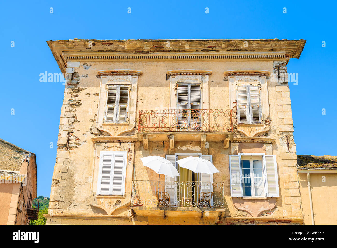 Deux parasols blancs sur le balcon d'une maison typique de la vieille ville à Erbalunga, Corse, France Banque D'Images
