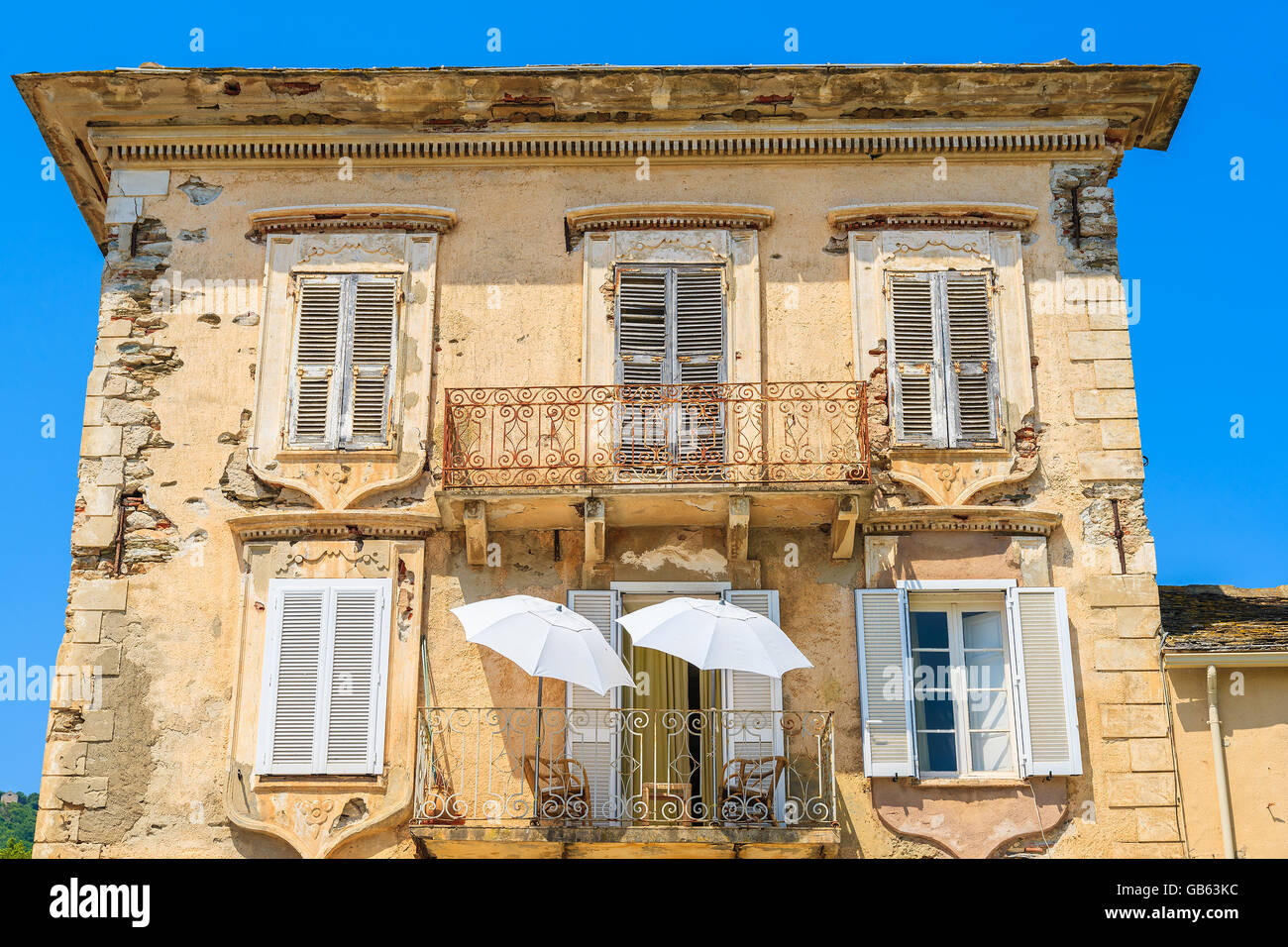 Deux parasols blancs sur le balcon d'une maison typique de la vieille ville à Erbalunga, Corse, France Banque D'Images