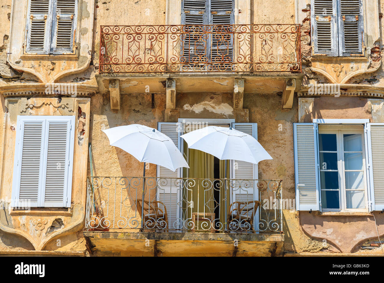 Deux parasols blancs sur le balcon d'une maison typique de la vieille ville à Erbalunga, Corse, France Banque D'Images