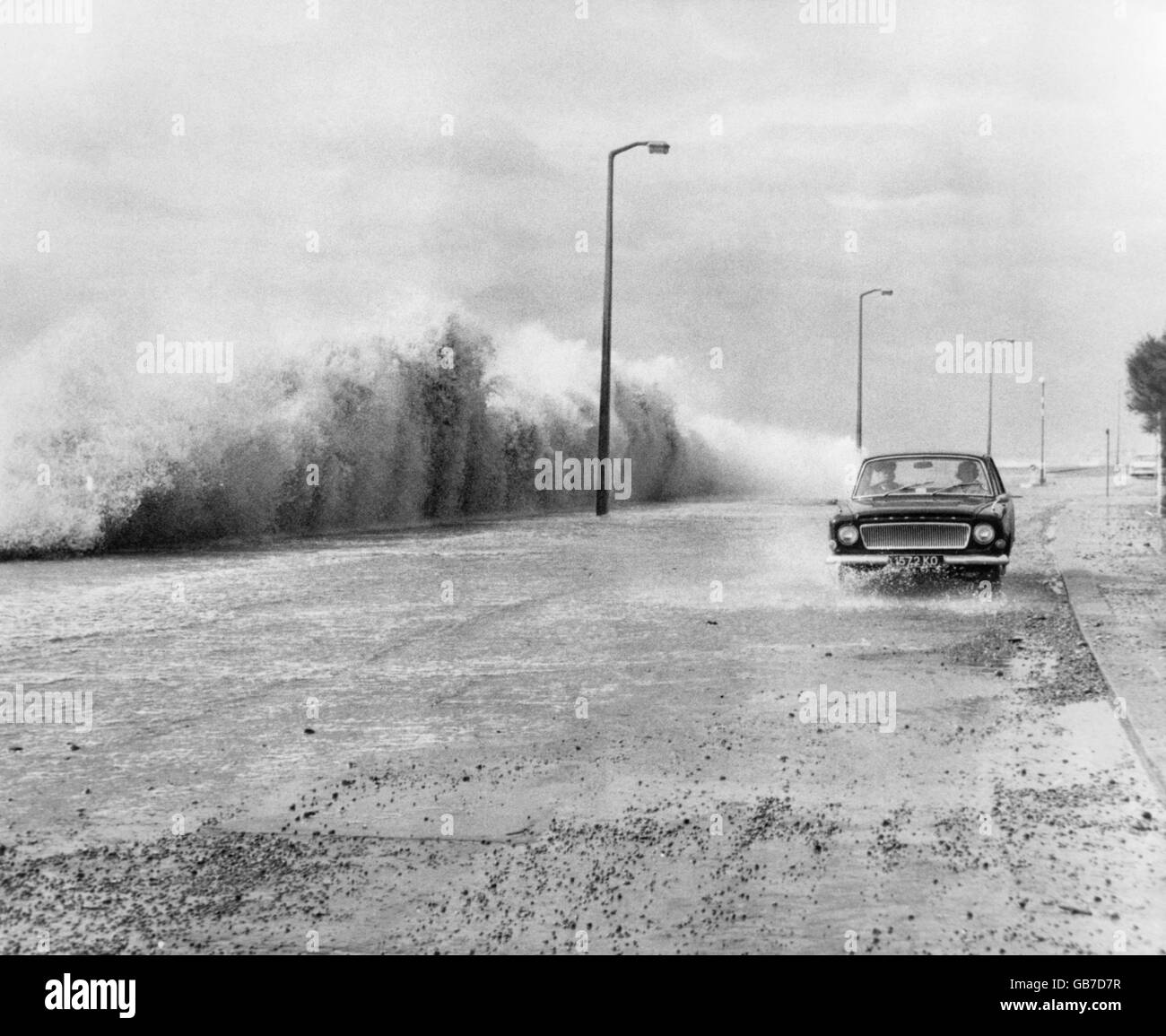 Le temps violent et les mers fortes batlent le chemin Sandgate, à Hythe, près de Folkestone, dans le Kent, couvrant la promenade avec des cailloux et de minuscules pierres, ce qui rend les conditions de conduite précaires. Banque D'Images