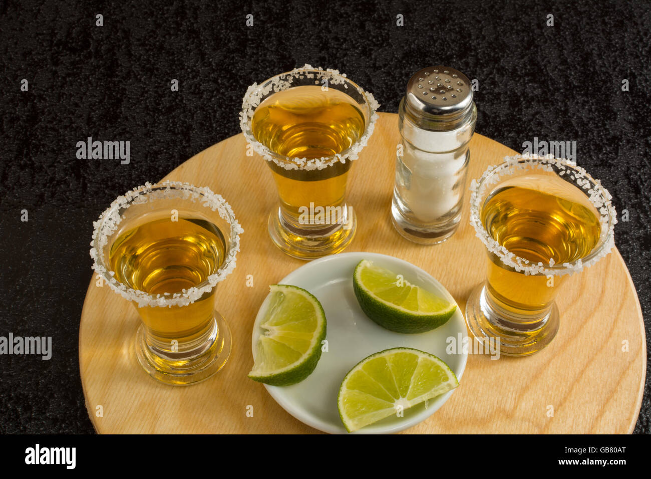 Trois coups de Fuissé avec de la chaux et le sel sur le fond noir. Shot de tequila. Gold tequila mexicaine. Tequila Banque D'Images