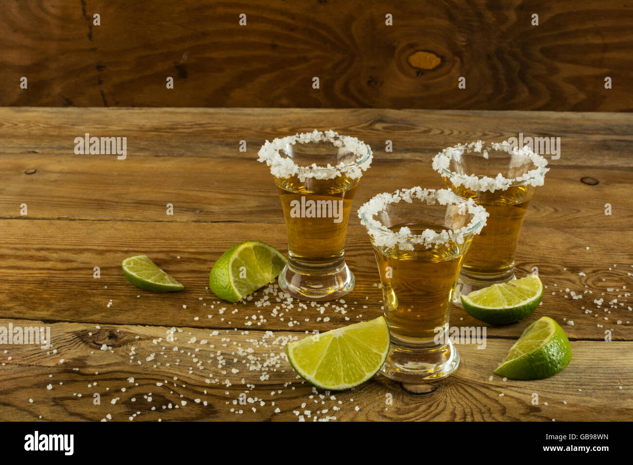 Trois coups de Fuissé avec de la chaux et du sel sur le fond en bois. Shot de tequila. Gold tequila mexicaine. Tequila Banque D'Images