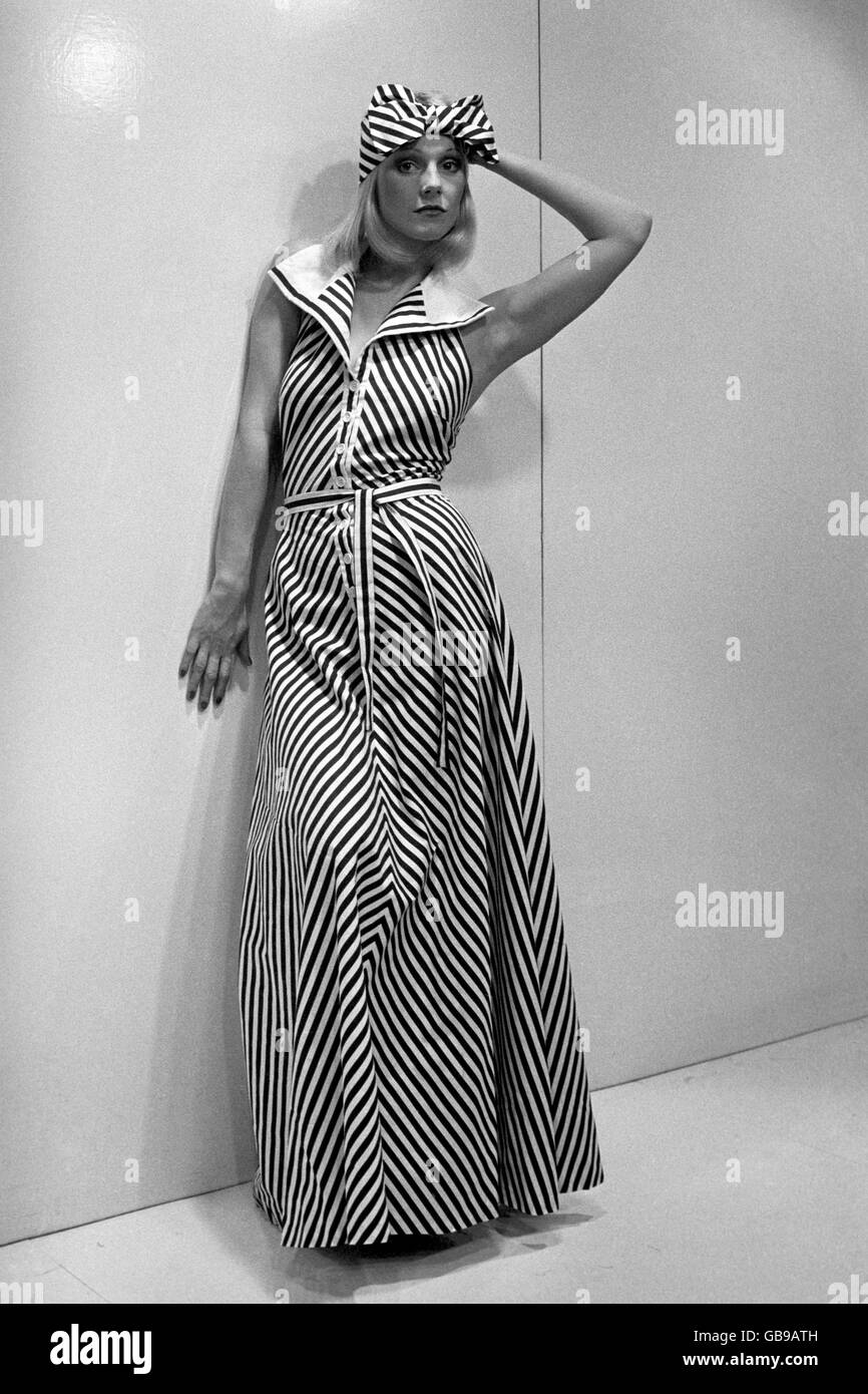 Annette porte une longue robe à col roulé marron et blanc et rayures, avec col piqué blanc, associée à un bandeau marron et blanc, de la collection d'été Mary quant pour 1975. Banque D'Images