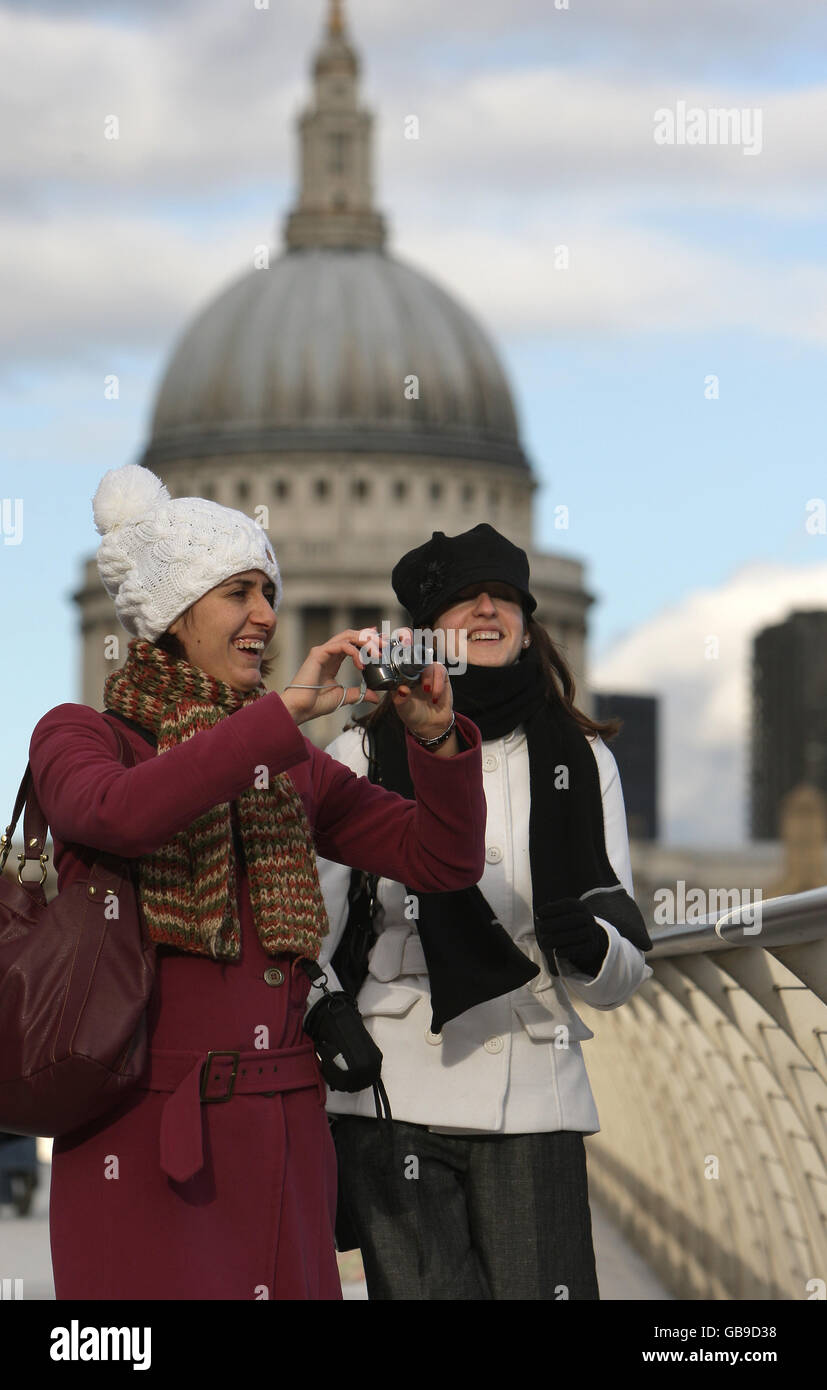 Les touristes en chapeaux et foulards prennent des photos du Millennium Bridge de Londres, alors qu'un front météorologique arctique arrive au Royaume-Uni. Banque D'Images