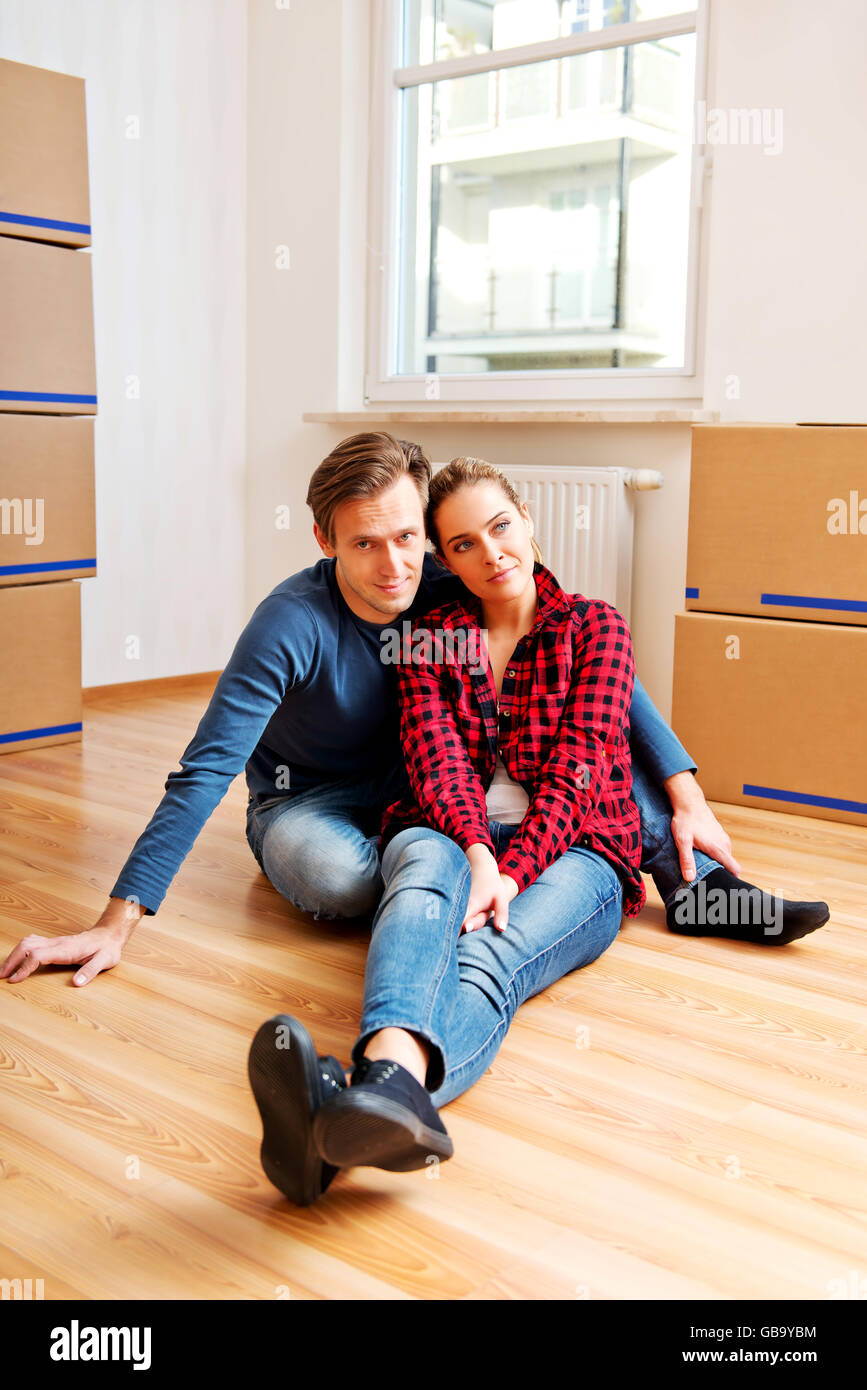 Yougn heureux couple assis sur le plancher d'une maison Banque D'Images