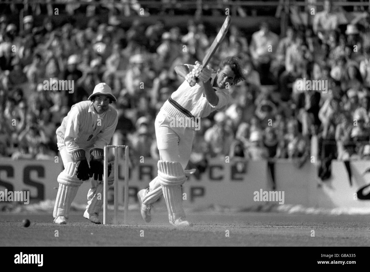 David Hookes (r), un australien, conduit le ballon jusqu'à la frontière, sous la surveillance du gardien de cricket de l'Angleterre Alan Knott (l) Banque D'Images