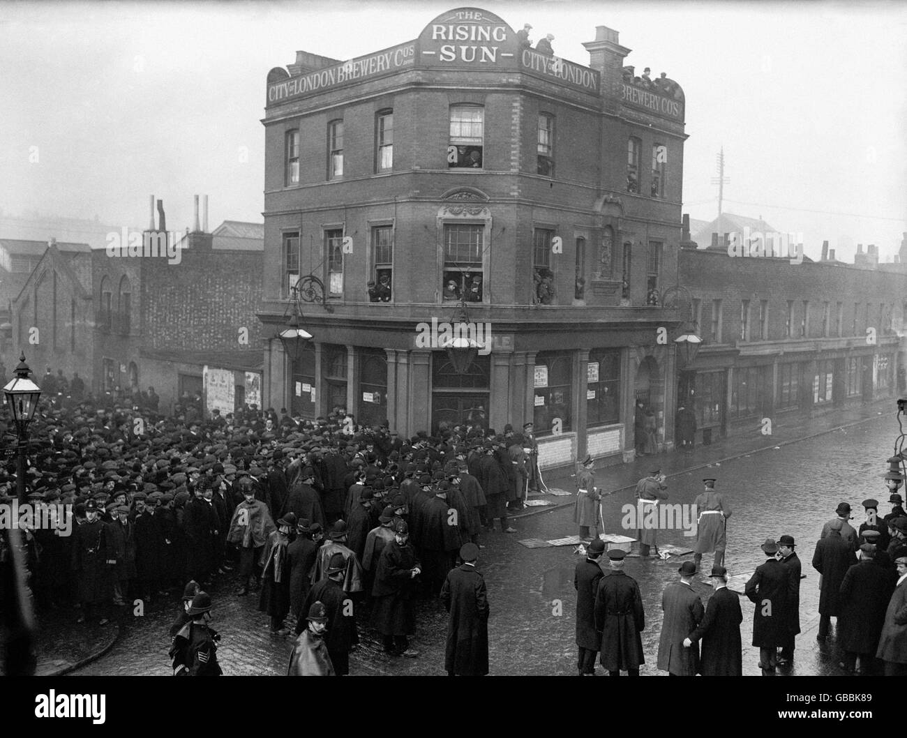 Des soldats en position de tir pendant le siège de Sidney Street, alors que la police tient une foule énorme pour essayer de voir la « bataille » Banque D'Images