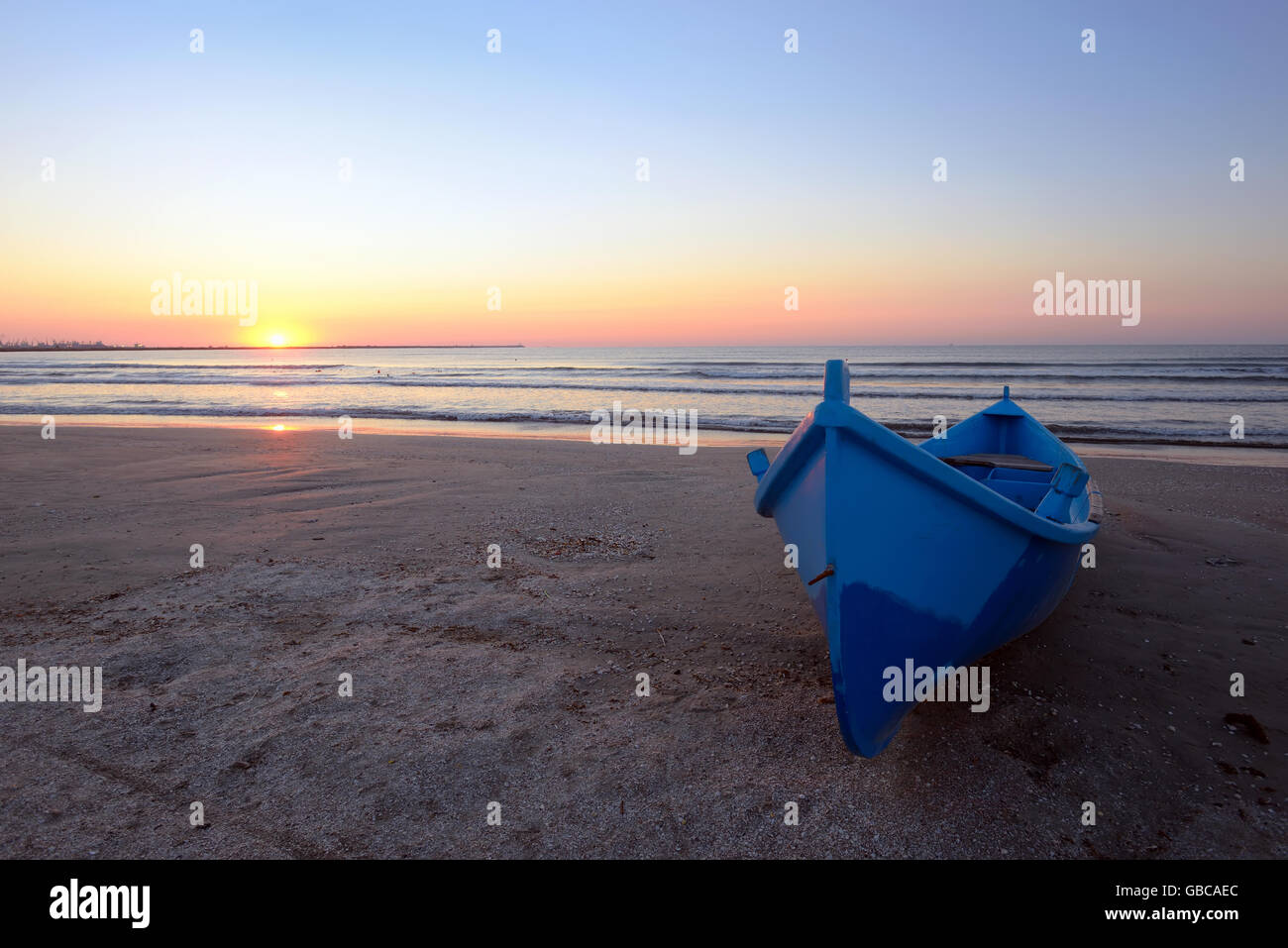 Bleu bateau sur la plage au lever du soleil Banque D'Images