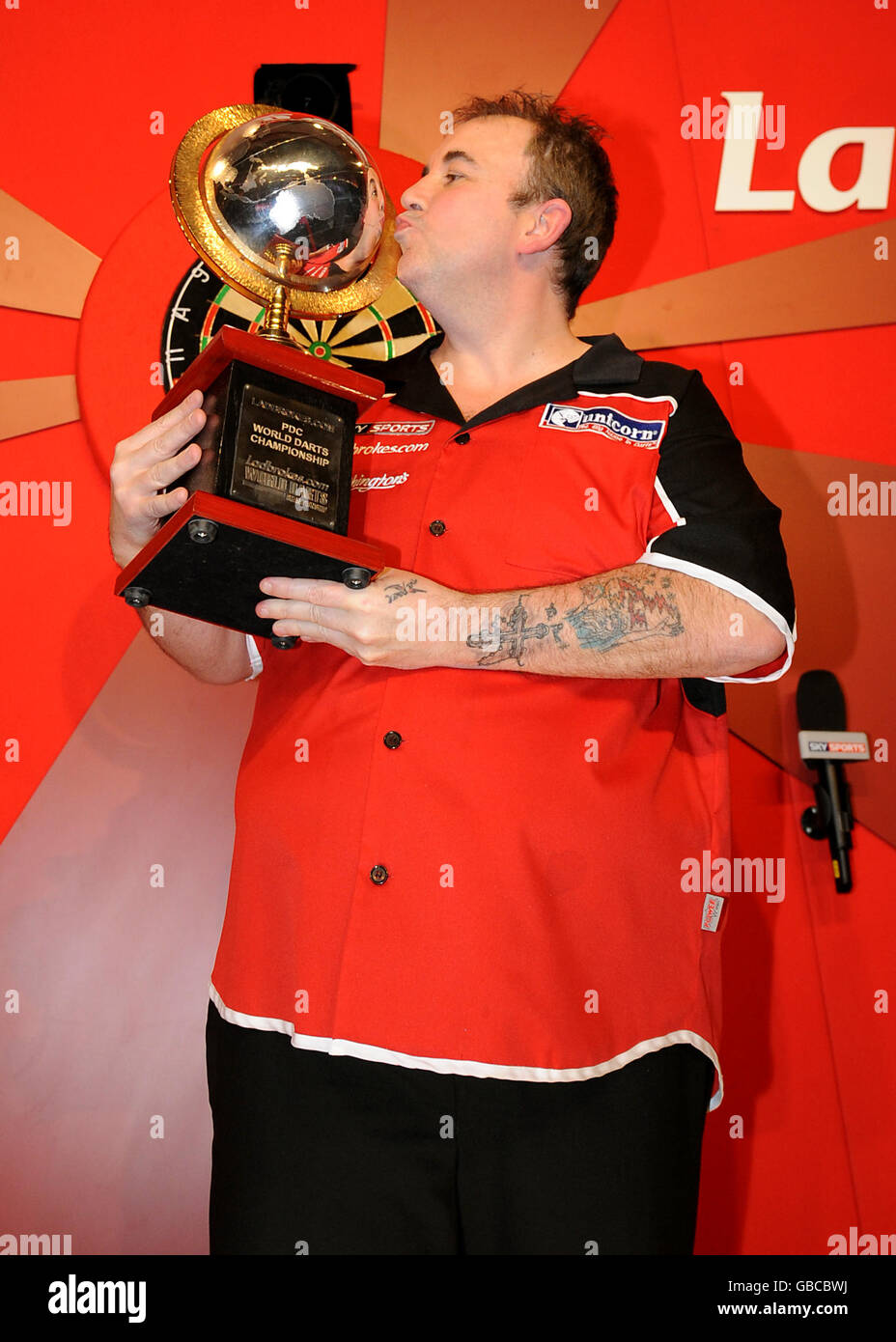 Phil Taylor embrasse le trophée après avoir remporté les fléchettes du monde Finale du championnat Banque D'Images