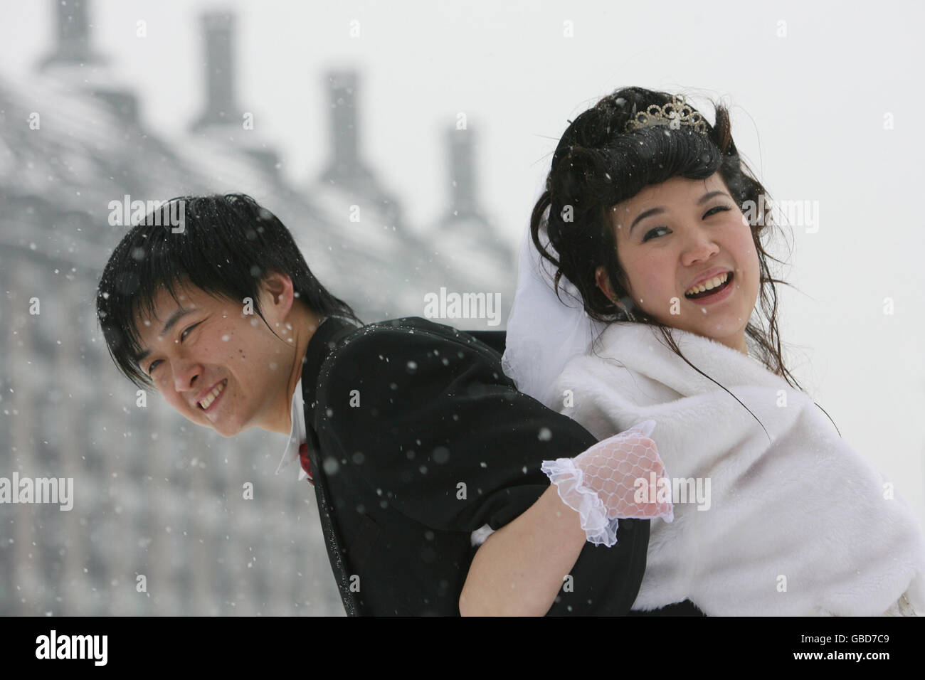 Zhou Hai Yan (à gauche) 25, et son nouveau wed Lin Chen, 23 ans, qui sont tous deux chinois mais vivent à Londres, célèbrent leur mariage alors que la neige tombe sur la place du Parlement, dans le centre de Londres. Banque D'Images