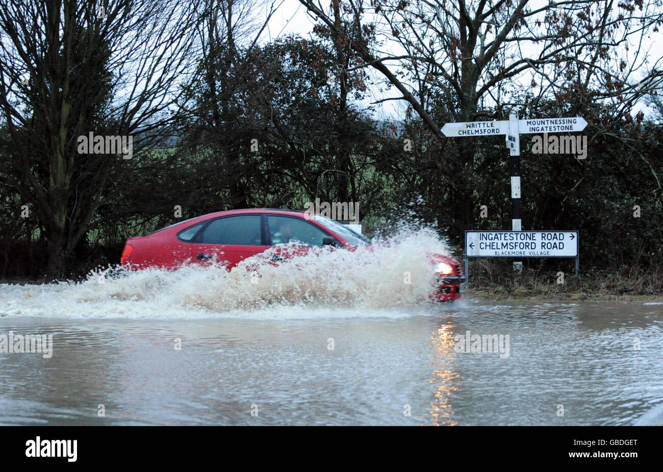 Une voiture traverse les eaux d'inondation du village de Blackmore, dans l'Essex. Banque D'Images