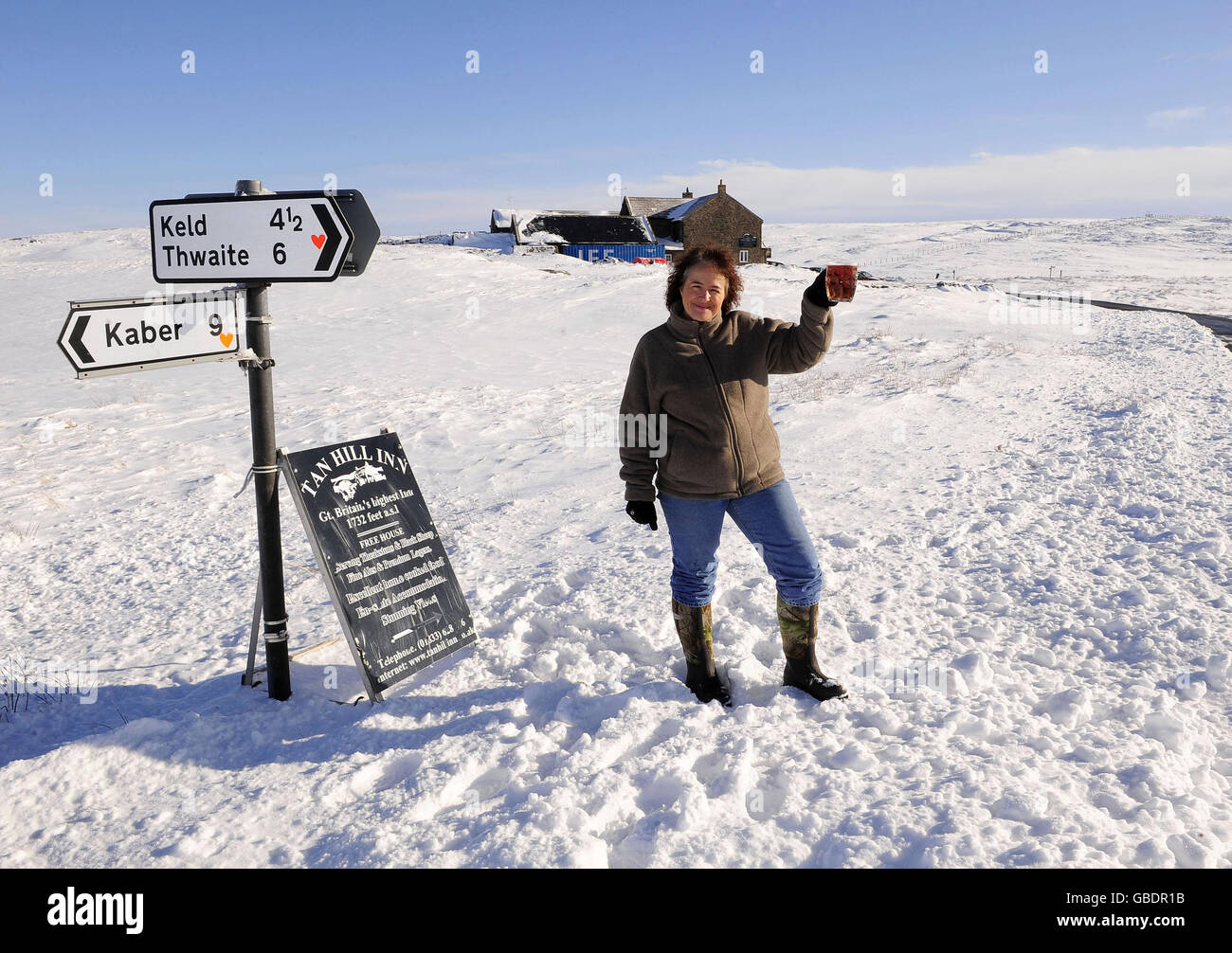 La dame de terre Tracy Daly pose devant le plus haut pub de Grande-Bretagne, le Tan Hill Inn, qui se trouve à 1732 mètres au sommet des Pennines. Banque D'Images