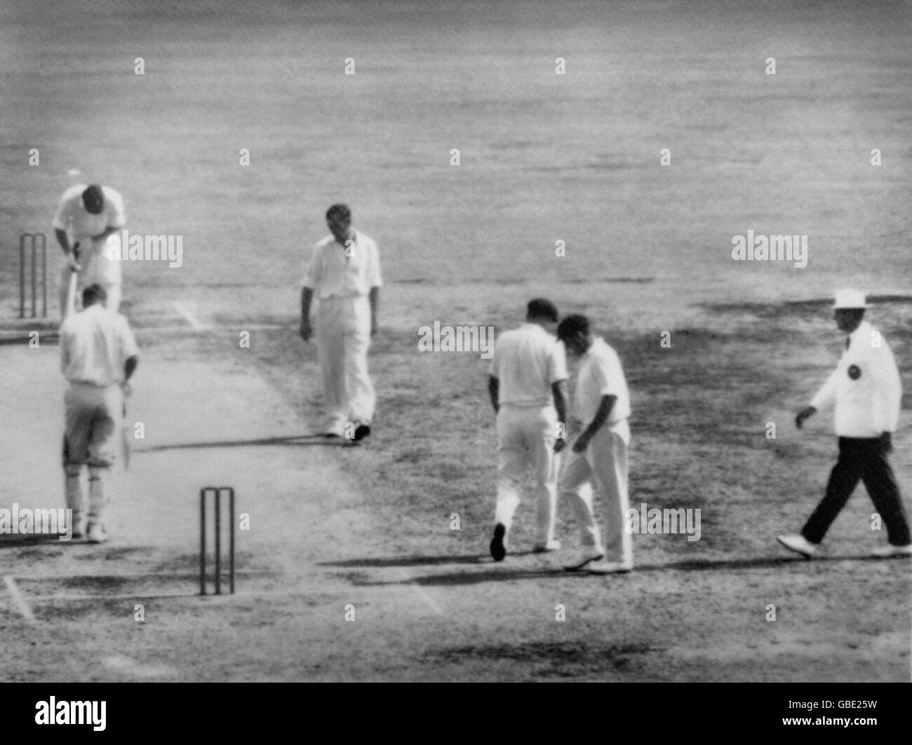 Deuxième jour du Test Match entre l'Australie et l'Afrique du Sud. Un Ian Meckiff abattu marche en arrière le long du cricket, après avoir été appelé 3 fois, est retiré par Richie Benaud. Les matraques sont Eddie Barlow (extrémité distante) Trevor Goddard (caméra la plus proche) extrême droite est l'arbitre Lou Rowan. Les autres agents de terrain sont Norm O'Neill et Tom Veivers. Banque D'Images