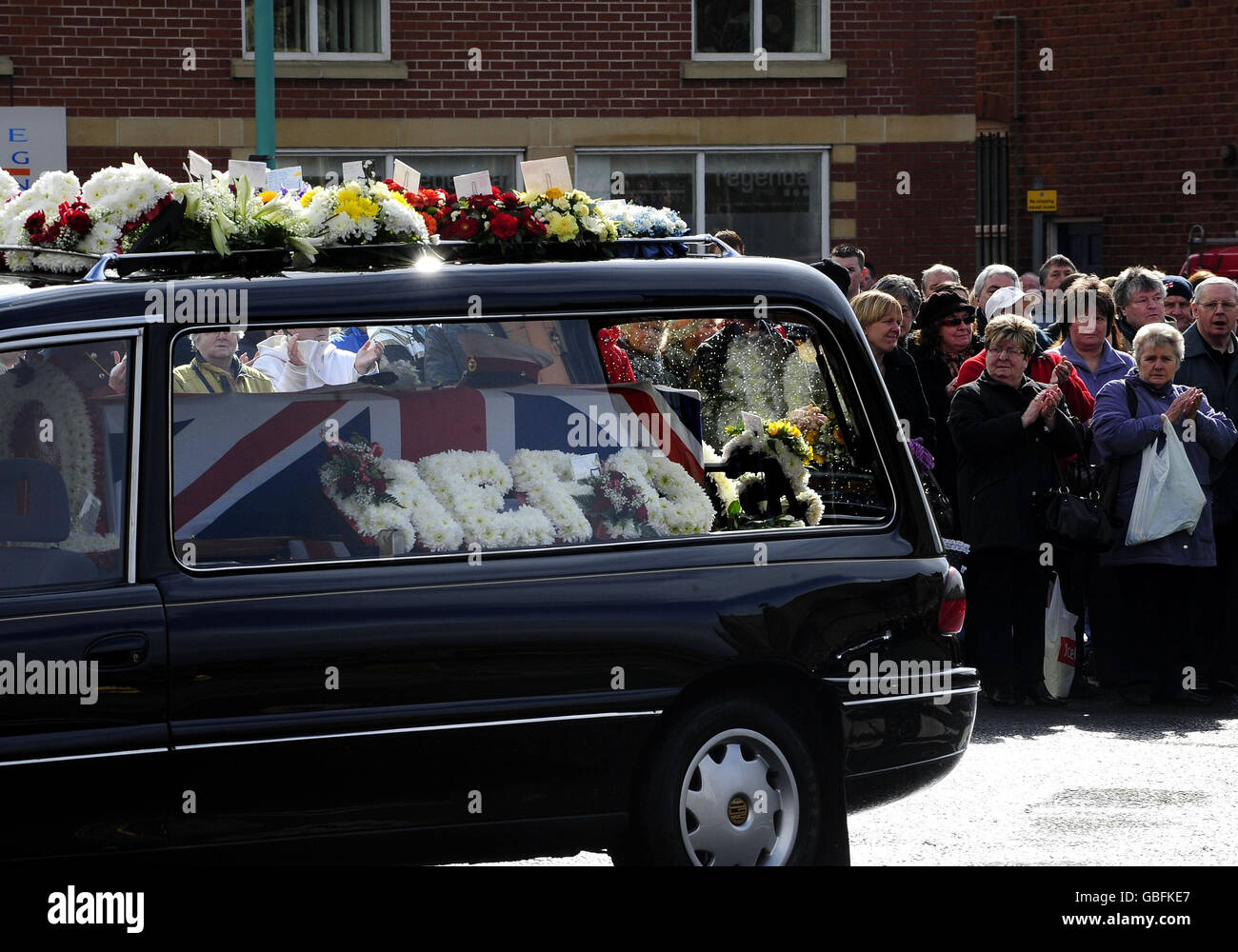 Les gens de Fleetwood paient leurs respects comme le corbillard avec des fleurs épelant le mot 'héros' mène le cortège de Royal Marine Darren Smith dont les funérailles ont eu lieu à Fleetwood. Banque D'Images