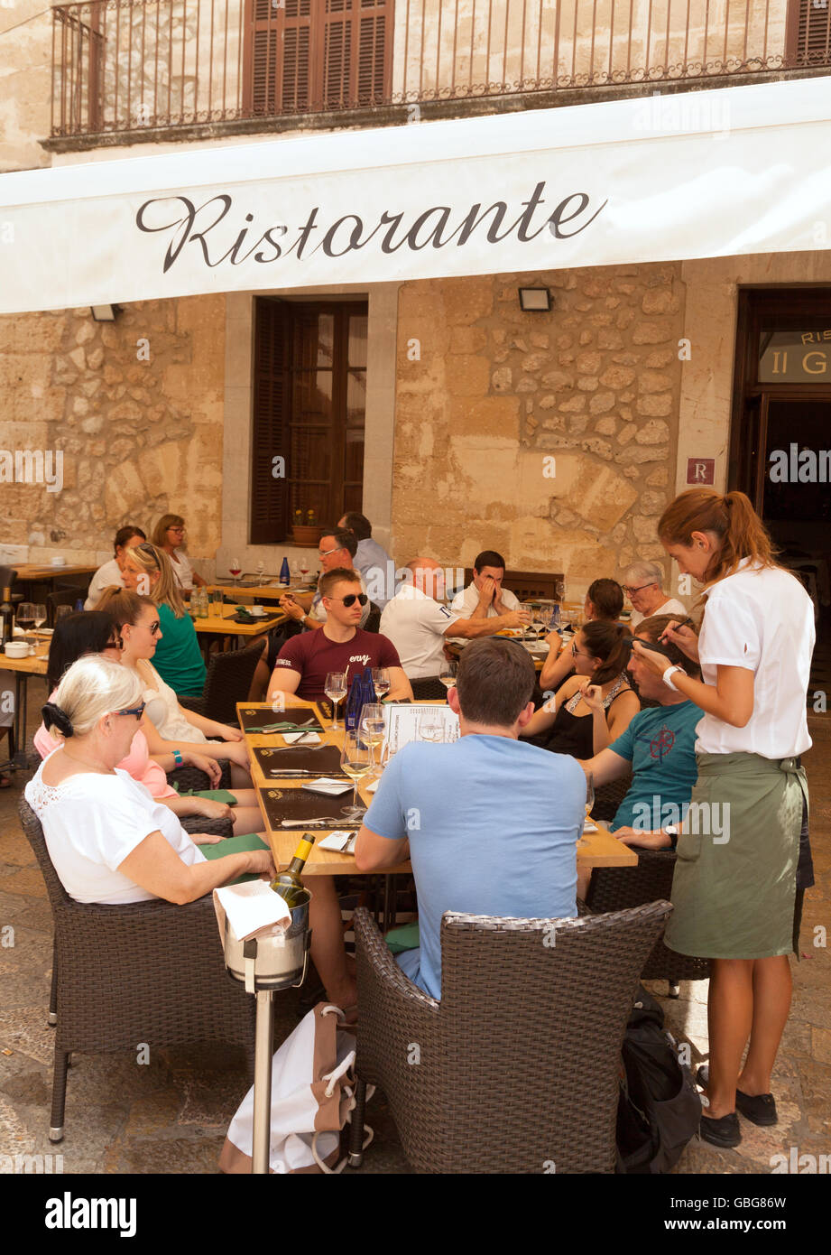 Serveuse prendre une commande de clients assis à l'extérieur dans un restaurant, Pollensa, Mallorca Majorque (Baléares, Espagne) Banque D'Images