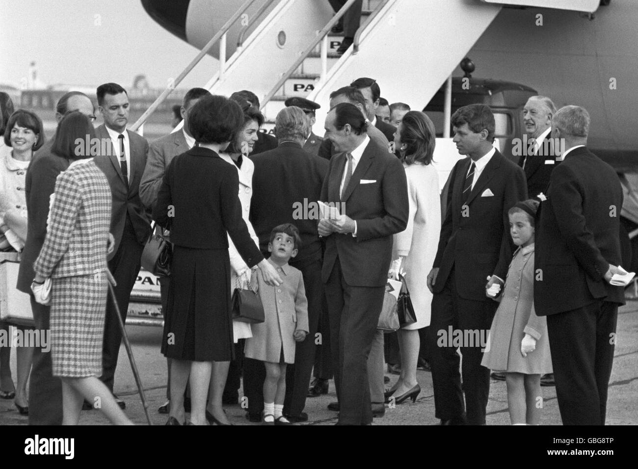 Jacqueline Kennedy entourée de membres de la famille à l'arrivée à l'aéroport de Londres par le Boeing 707 présidentiel américain. Elle tient la main de son fils, John Kennedy. À droite, le sénateur Robert Kennedy tient la main de la fille de Jacqueline, Caroline. Fond, (manteau blanc) est Lee Radziwill, sœur de Mme Kennedy. Jackie et des membres de la famille se sont envolés pour le dévoilement par la reine Elizabeth II du mémorial britannique de Runnymede pour assassiner le président américain John F Kennedy. Banque D'Images