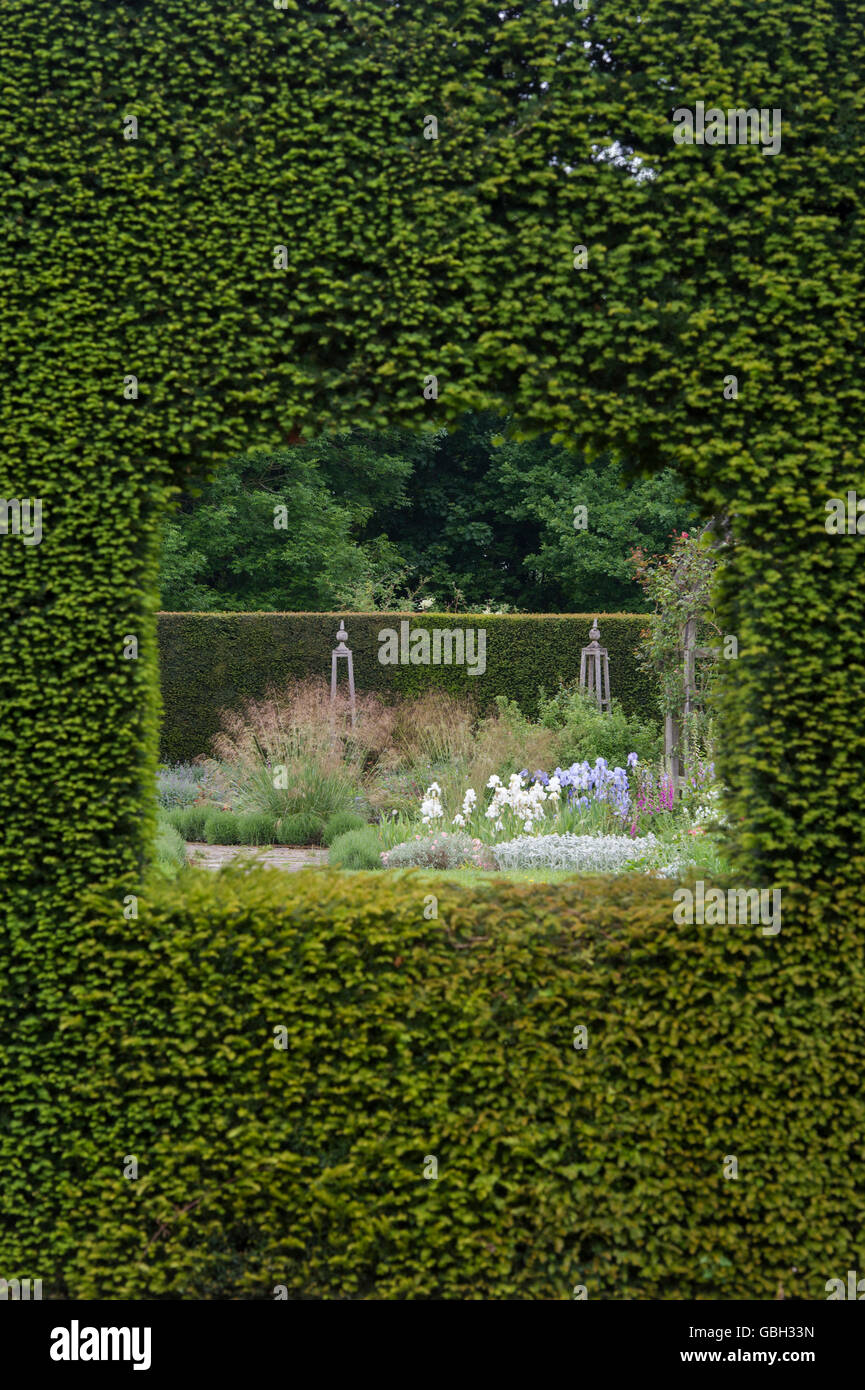 Regarder à travers un trou dans la haie d'if dans un jardin à Waterperry jardins, Wheatley, l'Oxfordshire. L'Angleterre Banque D'Images