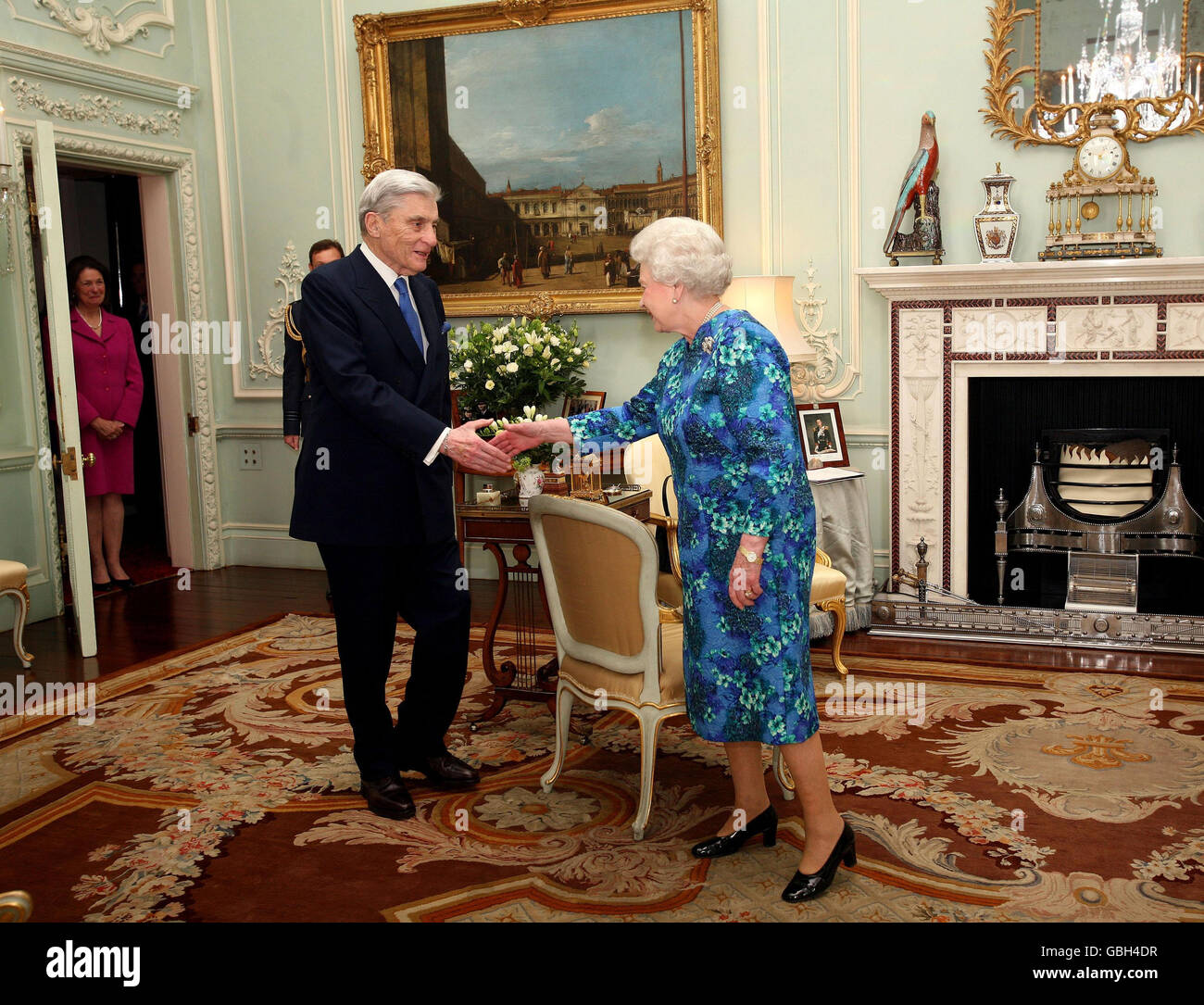 La reine Elizabeth II de Grande-Bretagne présente au sénateur américain John Warner un Chevalier honoraire commandant pour son travail de renforcement de l'alliance militaire américano-britannique. Il est surveillé par sa femme Jeanne Warner (à gauche) au Palais de Buckingham. Banque D'Images