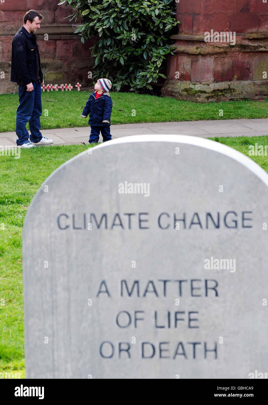 Les visiteurs se trouvent à proximité d'une tombe factice avec l'inscription « changement climatique, UNE question de vie ou de mort », à l'extérieur de la cathédrale de Coventry. La tombe a été placée là pour mettre en évidence l'effet négatif du changement climatique sur les personnes vivant dans les pays en développement. Banque D'Images